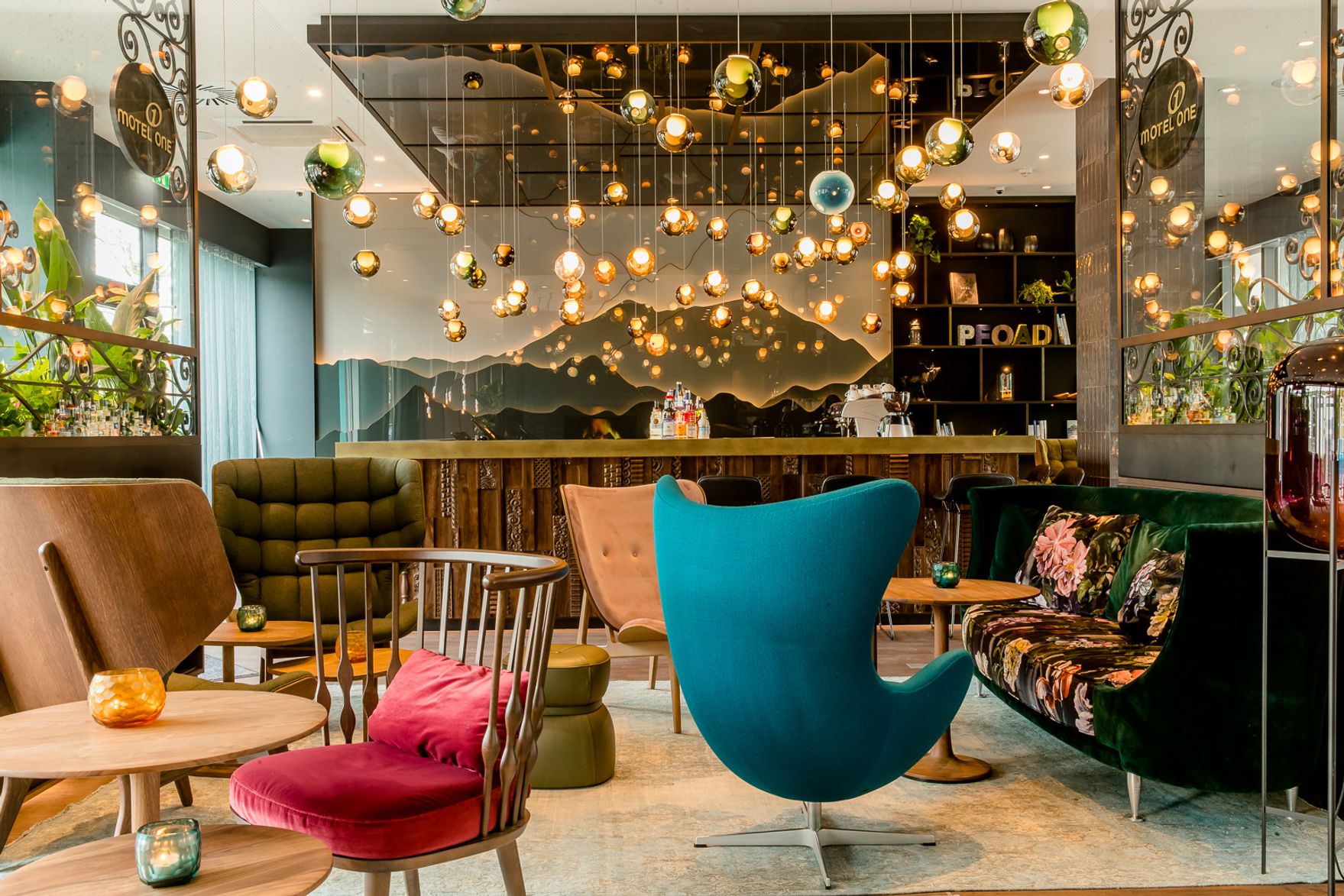 Gemütlicher Lounge-Bereich mit bunten Sesseln, stilvollen Tischen und moderner Beleuchtung, warmes Ambiente, ideal für entspannte Treffen oder kurze Pausen im Hotel.
