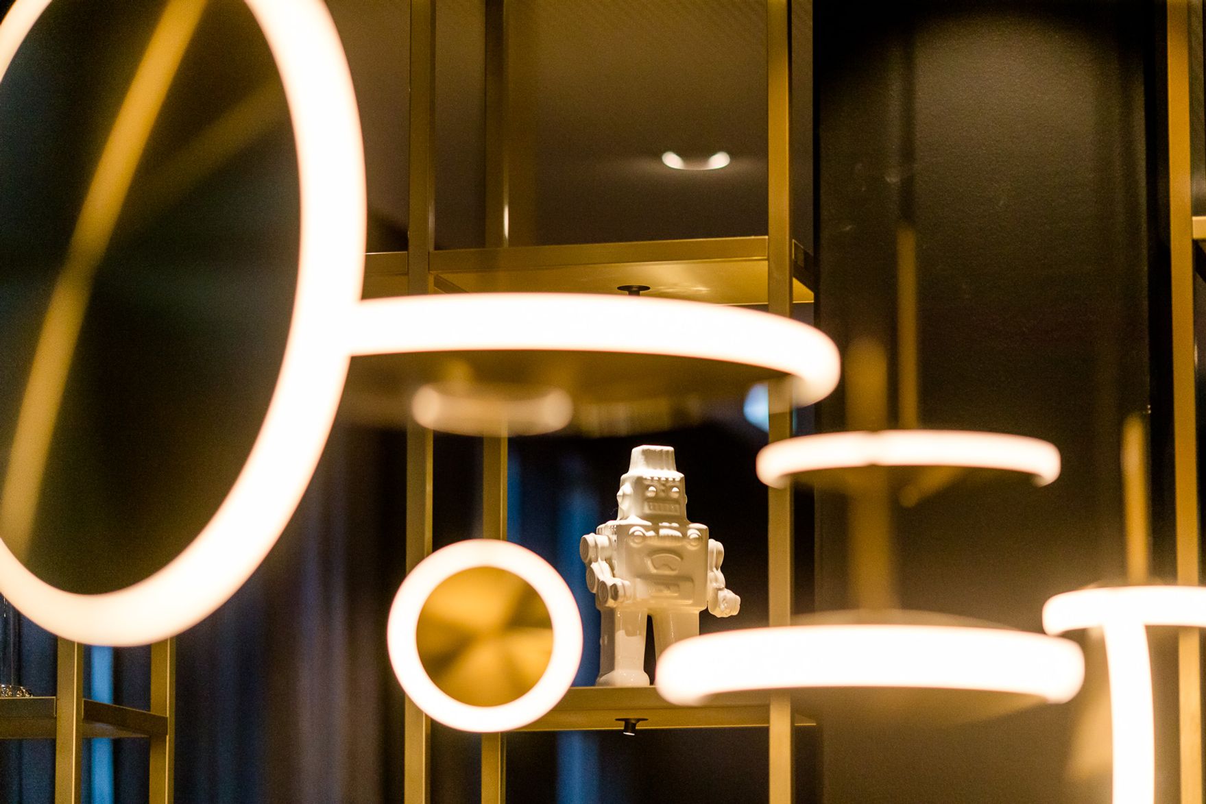 Moderne, stilvolle Beleuchtung mit runden, warm leuchtenden Lichtquellen und einer kleinen, weißen Roboterfigur als dekoratives Element in einem eleganten Innenraum.