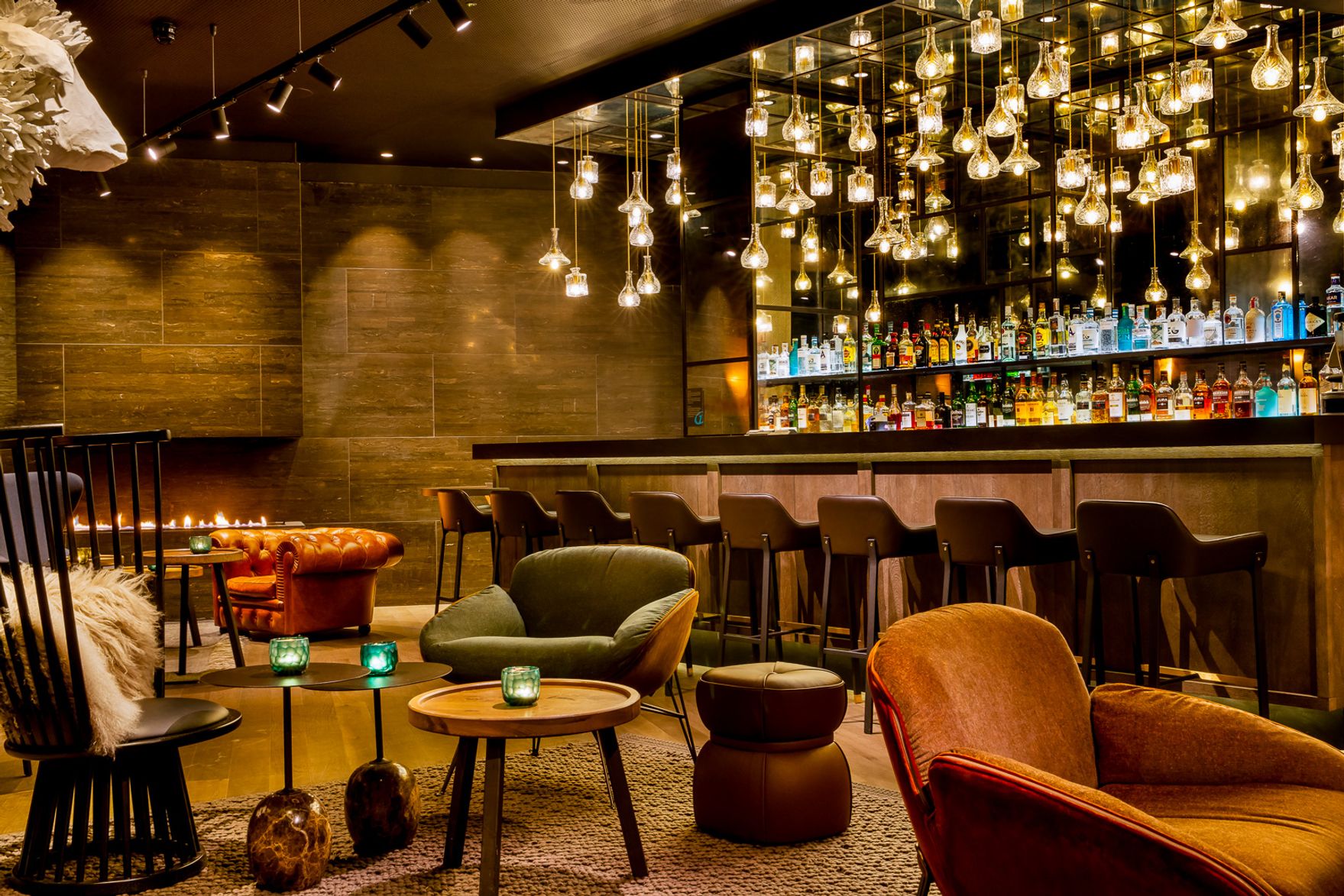 Gemütliche Hotelbar mit warmem Licht, modernen Sitzgelegenheiten und einer elegant beleuchteten Bar mit einer Vielfalt an Getränken im Hintergrund, ideal zum Entspannen und Geselligkeit.