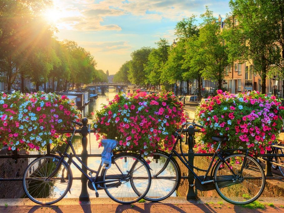 Blick auf eine Gracht in Amsterdam zum Sonnenaufgang - Teil einer fußläufigen City-Tour