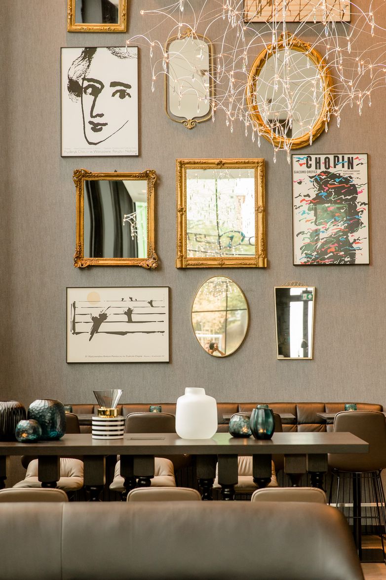 Wand mit verschiedenen Spiegeln und Kunstwerken in einem stilvollen, modernen Restaurant mit dekorativen Vasen und gemütlicher Atmosphäre.