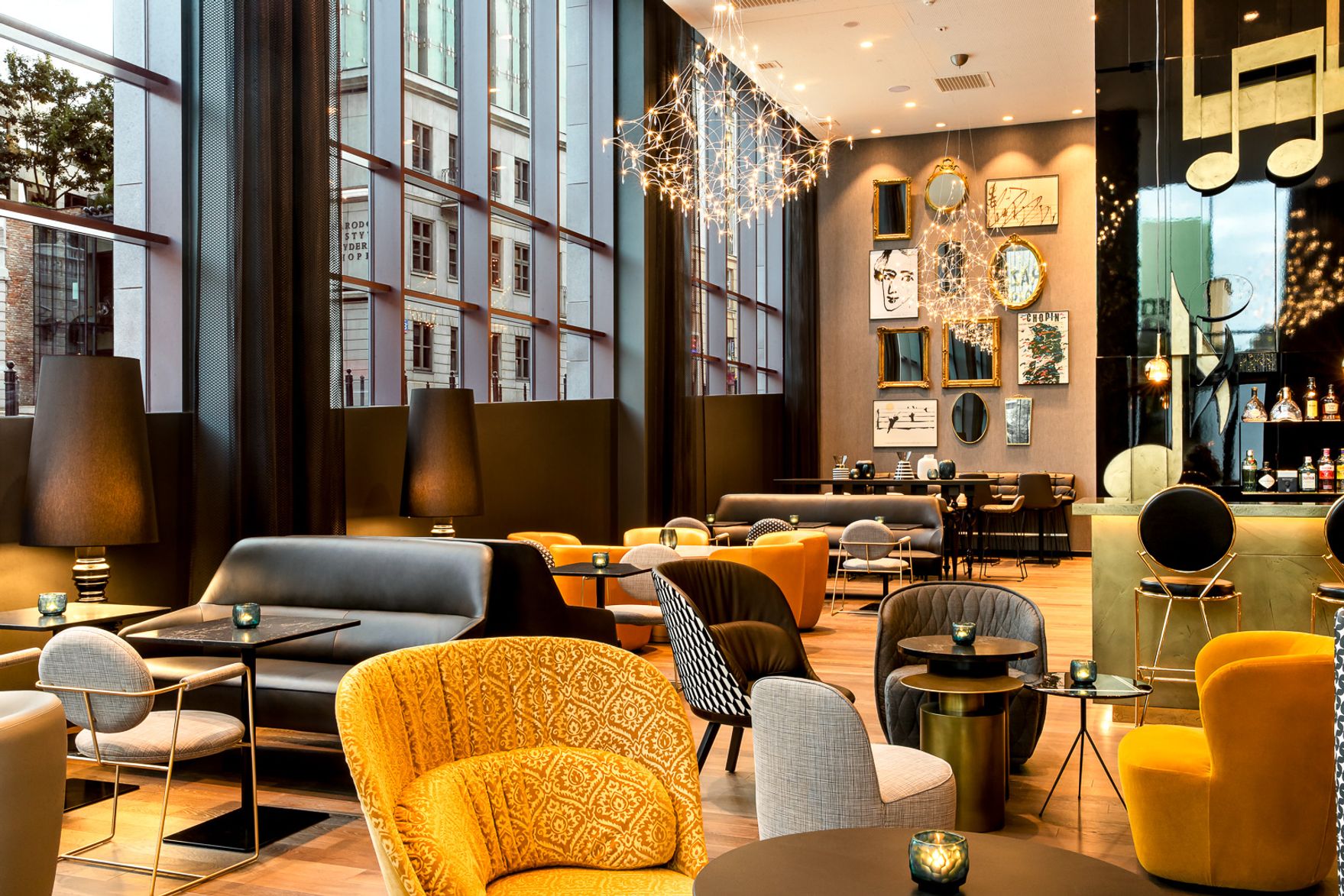 Gemütliche Hotel-Lounge mit großen Panoramafenstern, modernen Sitzmöbeln in warmen Farben und stilvollen Deckenleuchten, ideal für entspannte Gespräche oder einen Drink in eleganter Atmosphäre.