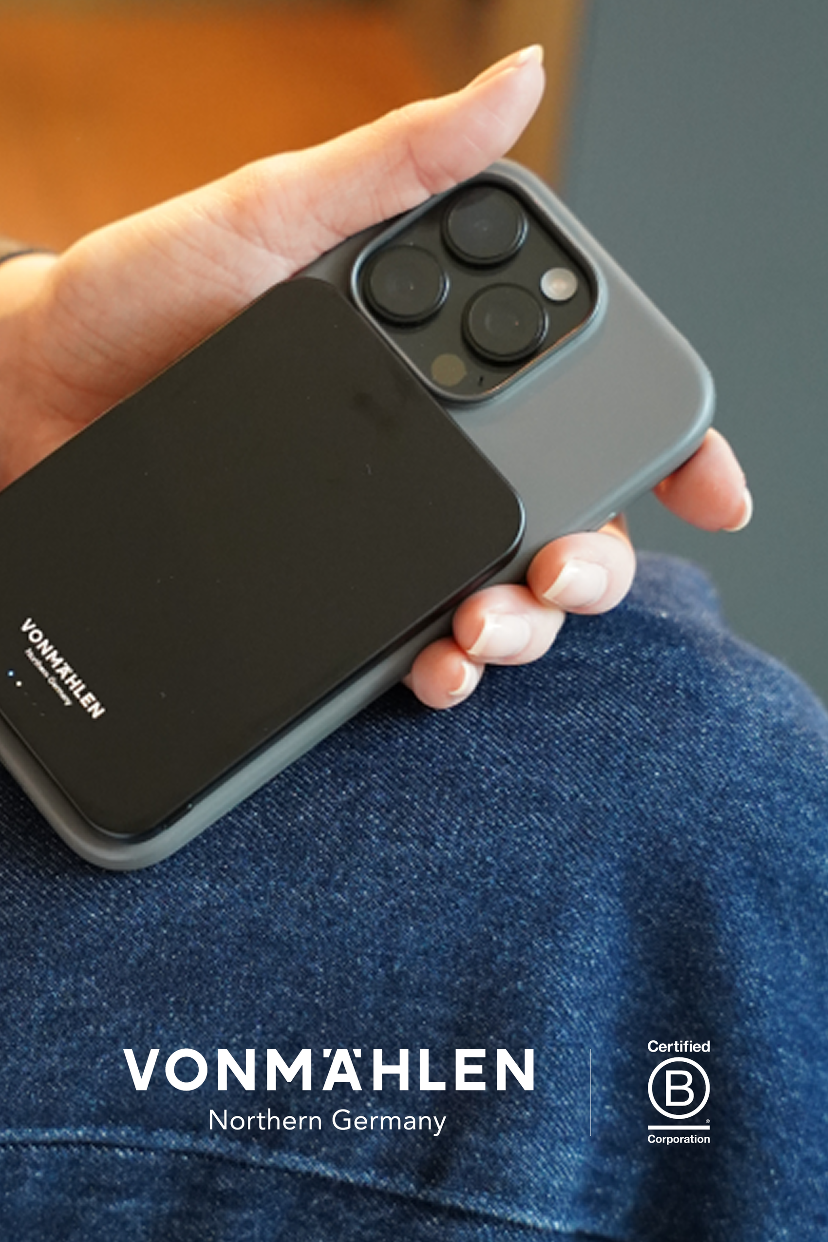 Hand hält ein Smartphone mit einer schwarzen, schlanken Powerbank von VONMÄHLEN, die das leichte und mobile Laden unterwegs symbolisiert.