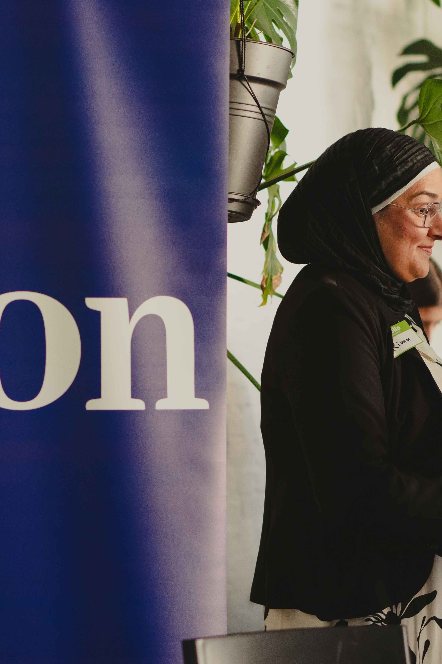 Auf dem Foto ist der Schriftzug der Firma Kiron erkennbar. Zudem sieht man eine Frau mit Kopftuch, die mit anderen Frauen im Gespräch ist.