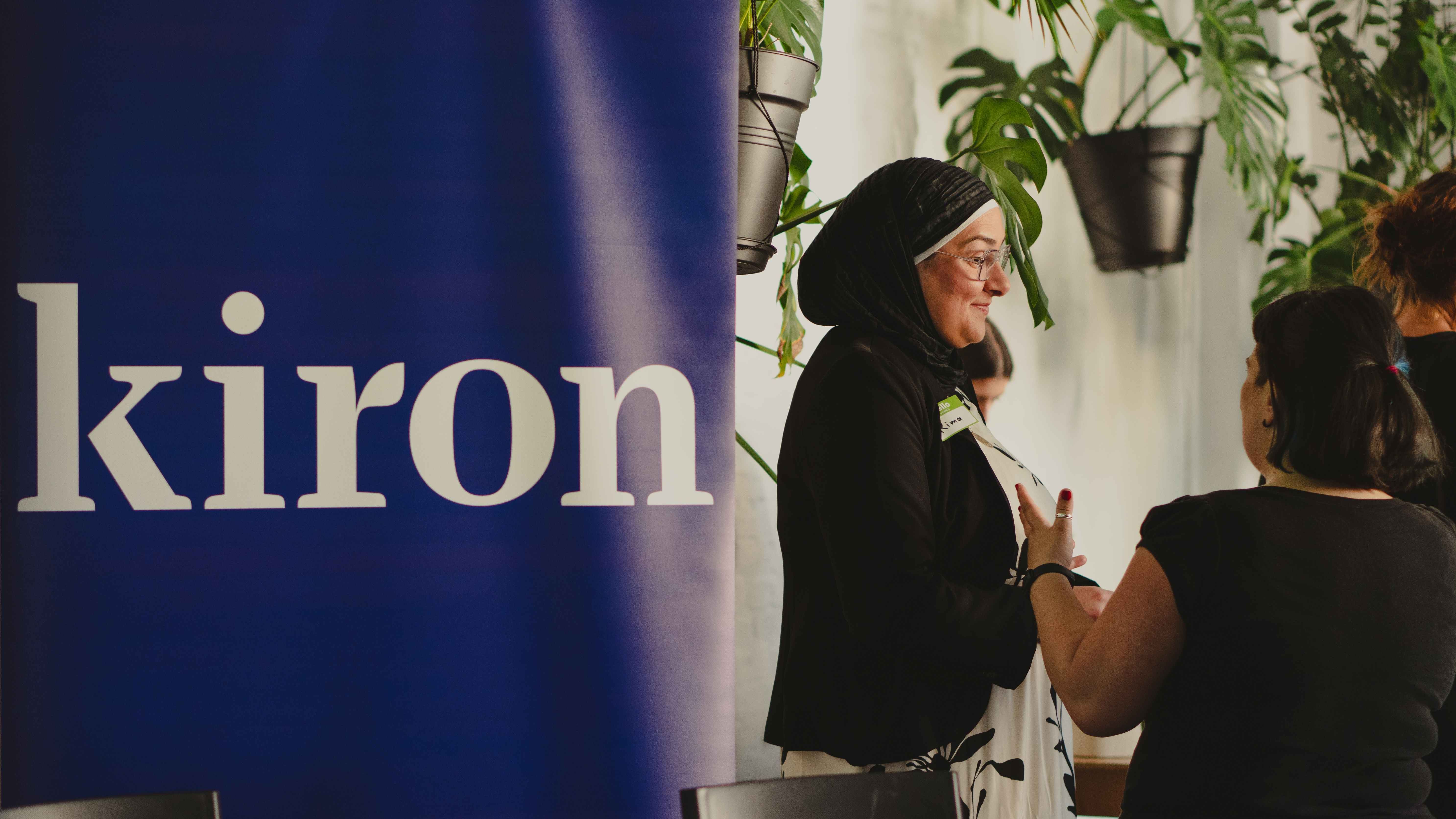 Auf dem Foto ist der Schriftzug der Firma Kiron erkennbar. Zudem sieht man eine Frau mit Kopftuch, die mit anderen Frauen im Gespräch ist. Auf dem Foto ist der Schriftzug der Firma Kiron erkennbar. Zudem sieht man eine Frau mit Kopftuch, die mit anderen Frauen im Gespräch ist.