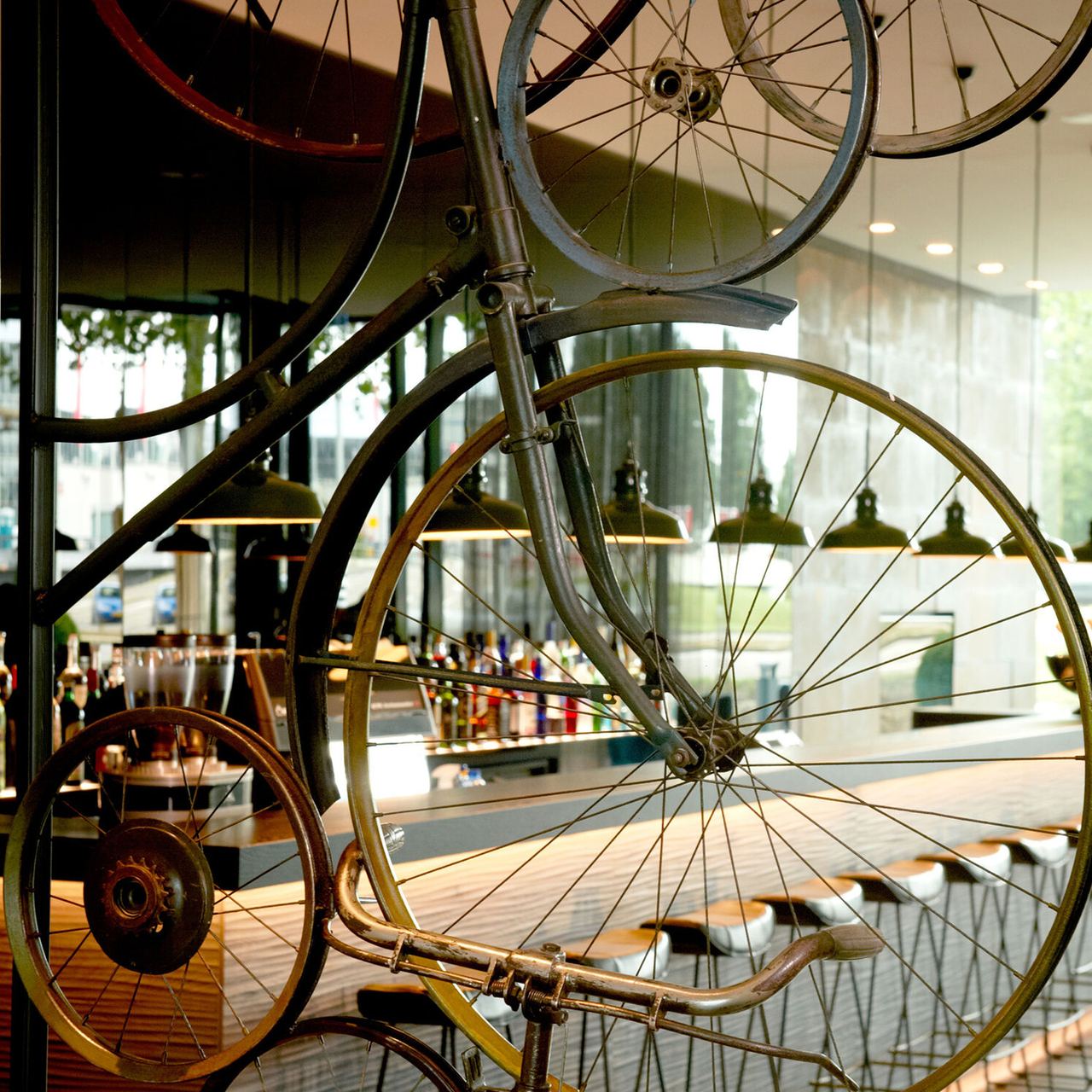 Antikes Hochrad-Fahrrad als dekoratives Element vor moderner Motel One Hotelbar mit gemütlicher Atmosphäre und stilvoller Beleuchtung.