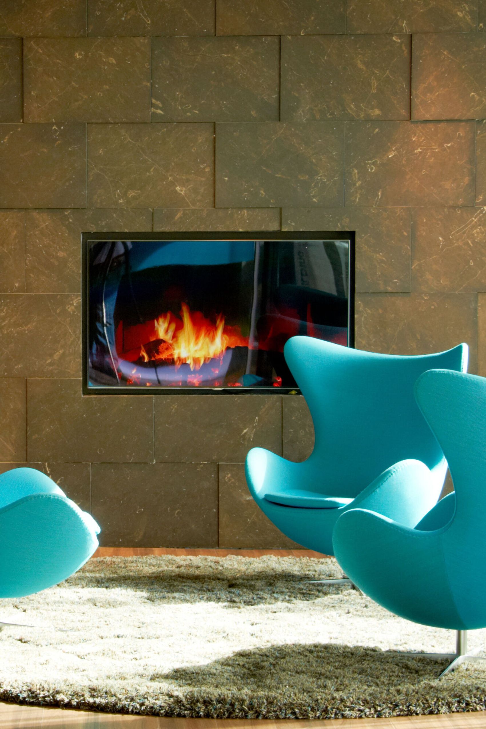 hotel Amsterdam Motel One three egg chairs in front of a TV with a fireplace image