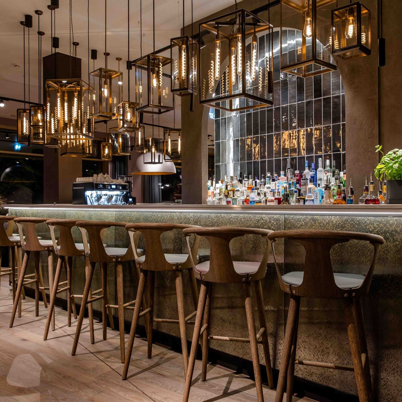 Motel One Hotelbar mit eleganter Beleuchtung, Holzstühlen und gut bestückter Bar. .