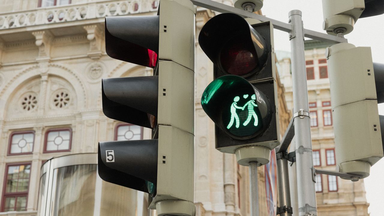 Eine Fußgängerampel mit grünem Lichtsignal, das eine Familie mit zwei Erwachsenen und einem Kind darstellt, symbolisiert sicheres Überqueren der Straße. Eine Fußgängerampel mit grünem Lichtsignal, das eine Familie mit zwei Erwachsenen und einem Kind darstellt, symbolisiert sicheres Überqueren der Straße.
