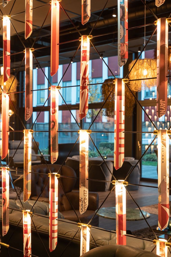 [Translate to Deutsch:] Designhotel Berlin Spittelmarkt Motel One Blick durch leuchtende Stäbe hindurch in eine große Lounge mit Sitzgelegenheiten