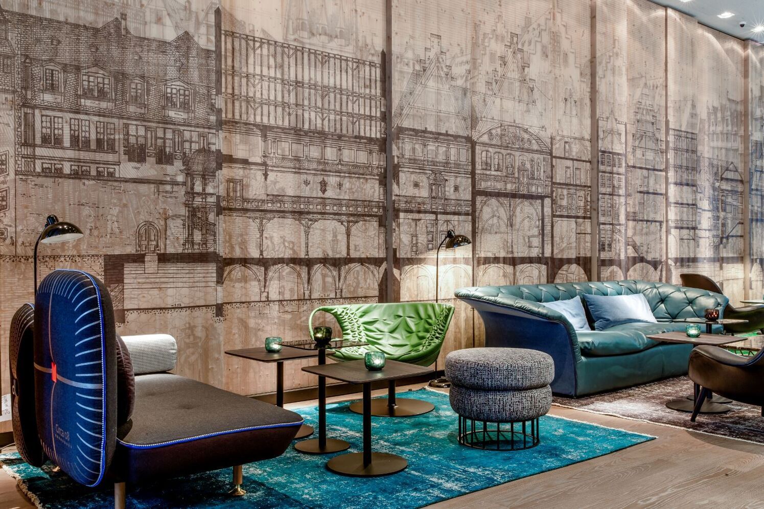 Moderne Lounge mit stilvollen Sitzmöbeln in Blau und Grün, runden schwarzen Tischen und einer Wandgestaltung mit historischen Gebäudezeichnungen