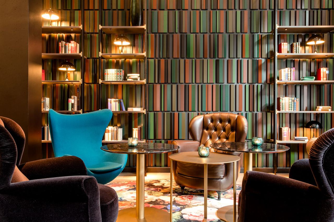 Hotel Frankfurt Römer Motel One Lounge mit Sesseln, einem Egg chair in türkis und Bücherregalen