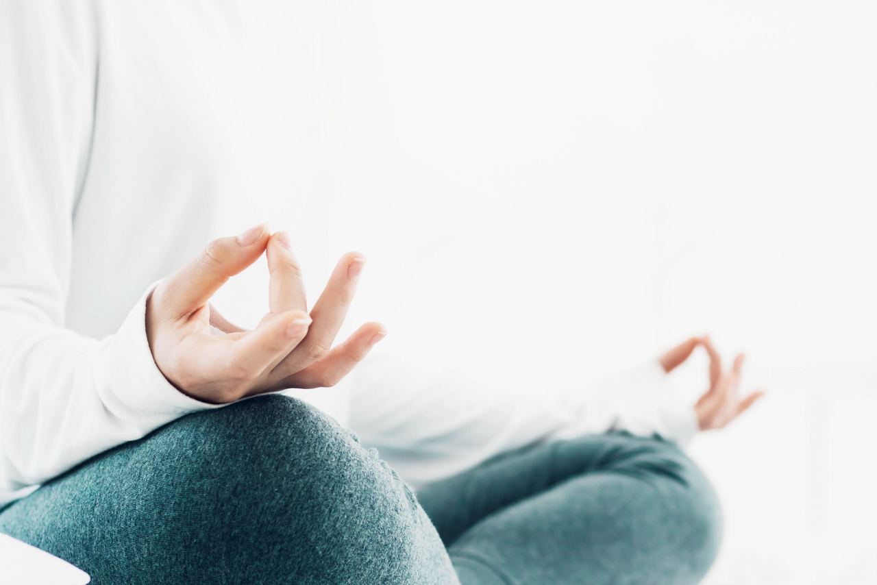 Nahaufnahme auf eine meditierende Person im Schneidersitz