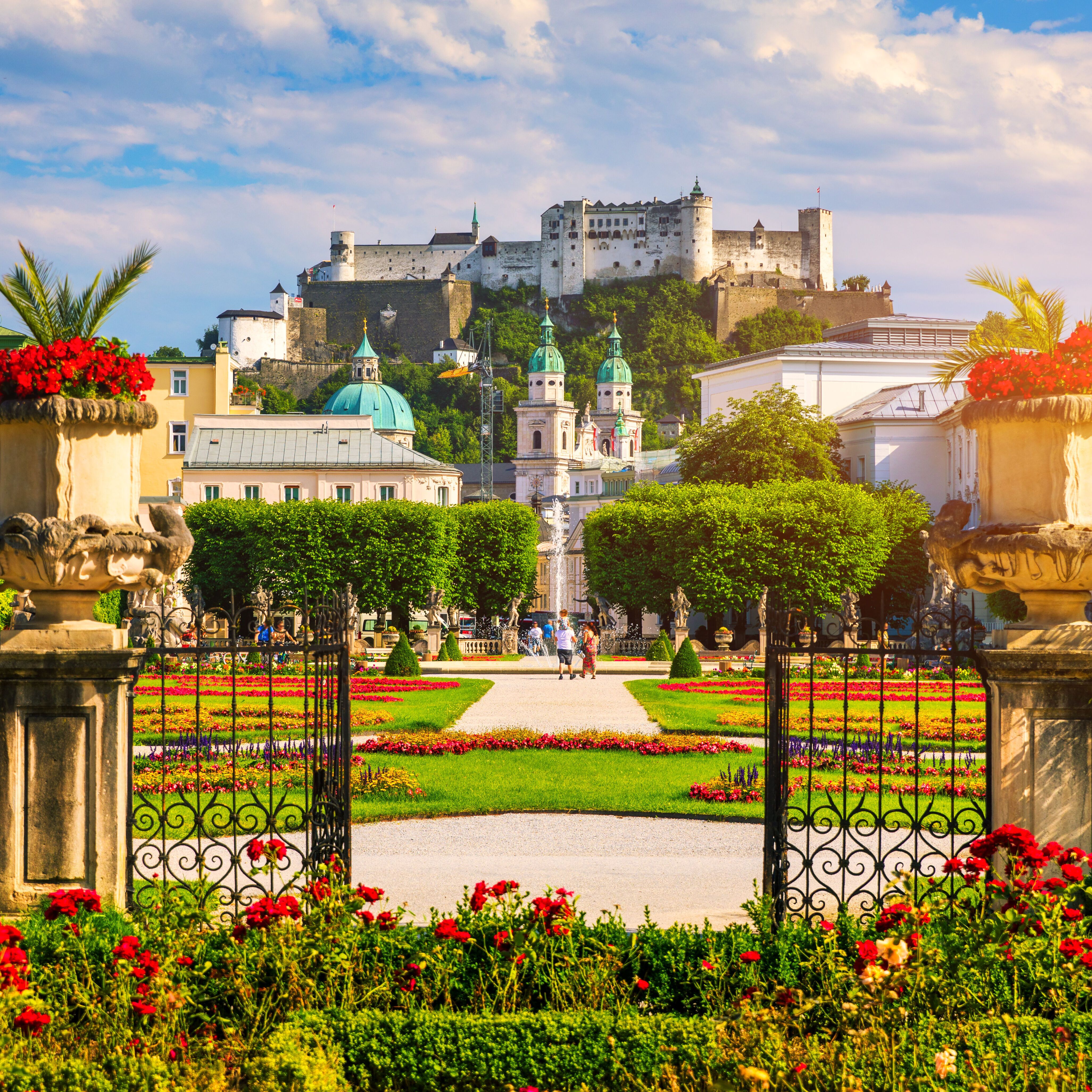 Motel One Mirabell Garten blüht unter der Sonne im Hintergrund die Stadt