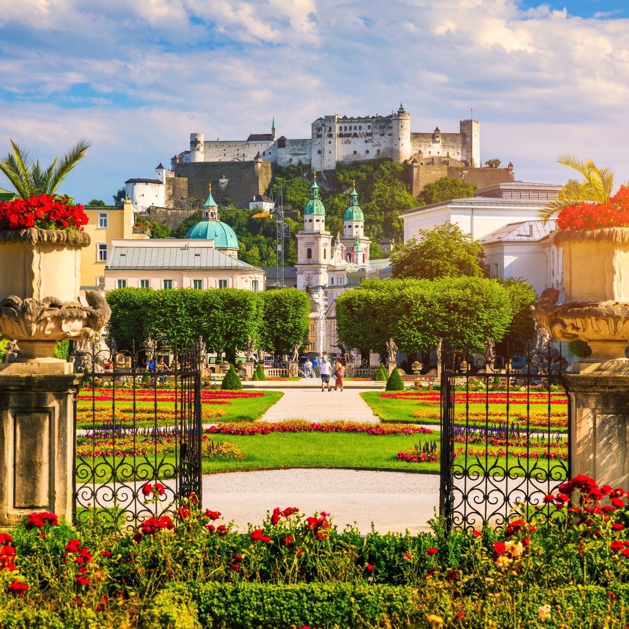 Motel One Mirabell Garten blüht unter der Sonne im Hintergrund die Stadt