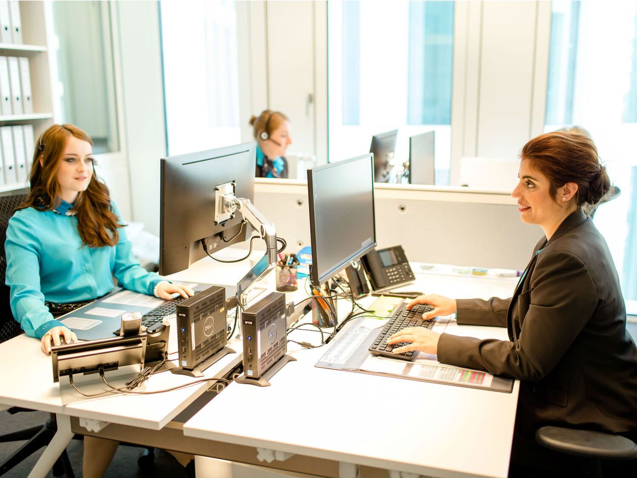 Zwei Frauen arbeiten am Schreibtisch in einem Büro, konzentriert am Computer.