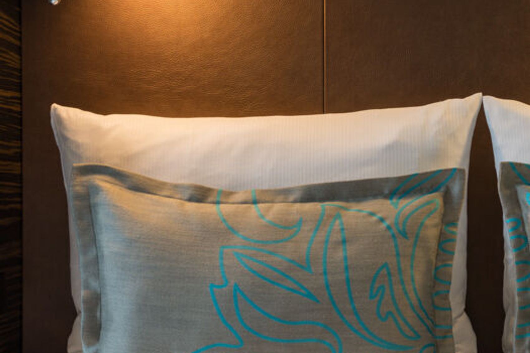Designhotel Leipzig Nikolaikirche Motel One Doppelbett mit zwei weißen Kissen sowie zwei gemusterten Zierkissen