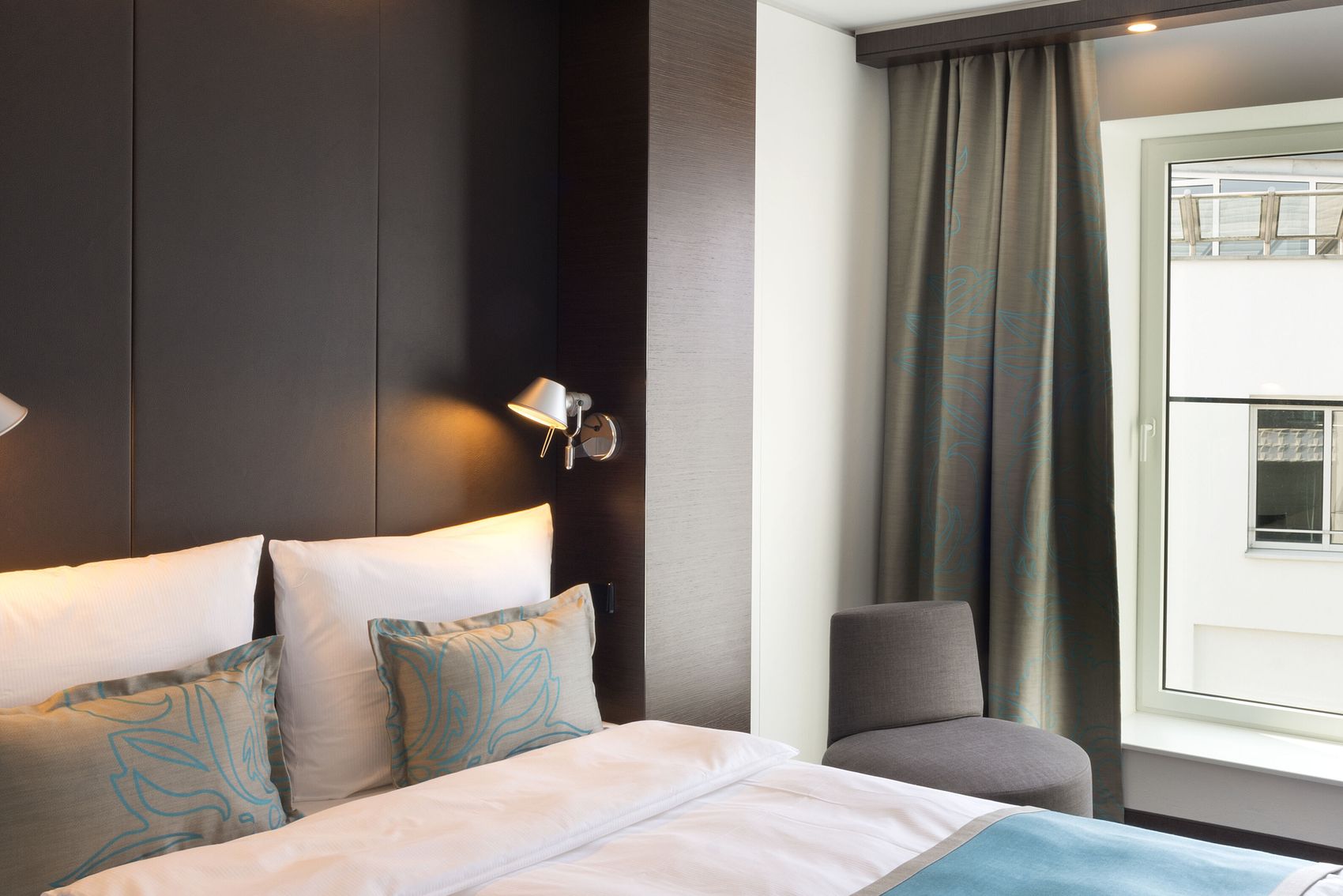 Hotel Leipzig Augustusplatz Motel One geräumiges Zimmer mit großem Bett sowie Sessel und Schreibtisch