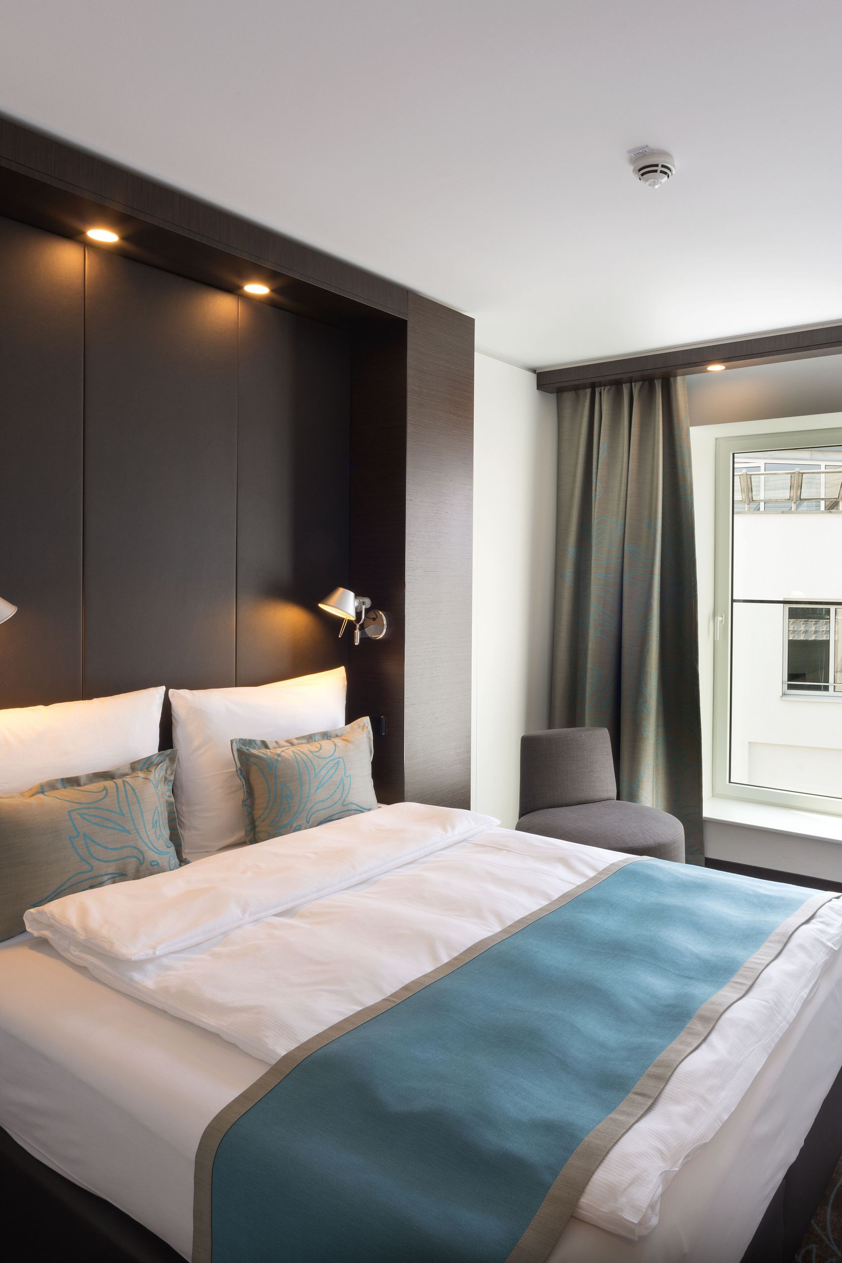 Hotel Leipzig Augustusplatz Motel One geräumiges Zimmer mit großem Bett sowie Sessel und Schreibtisch