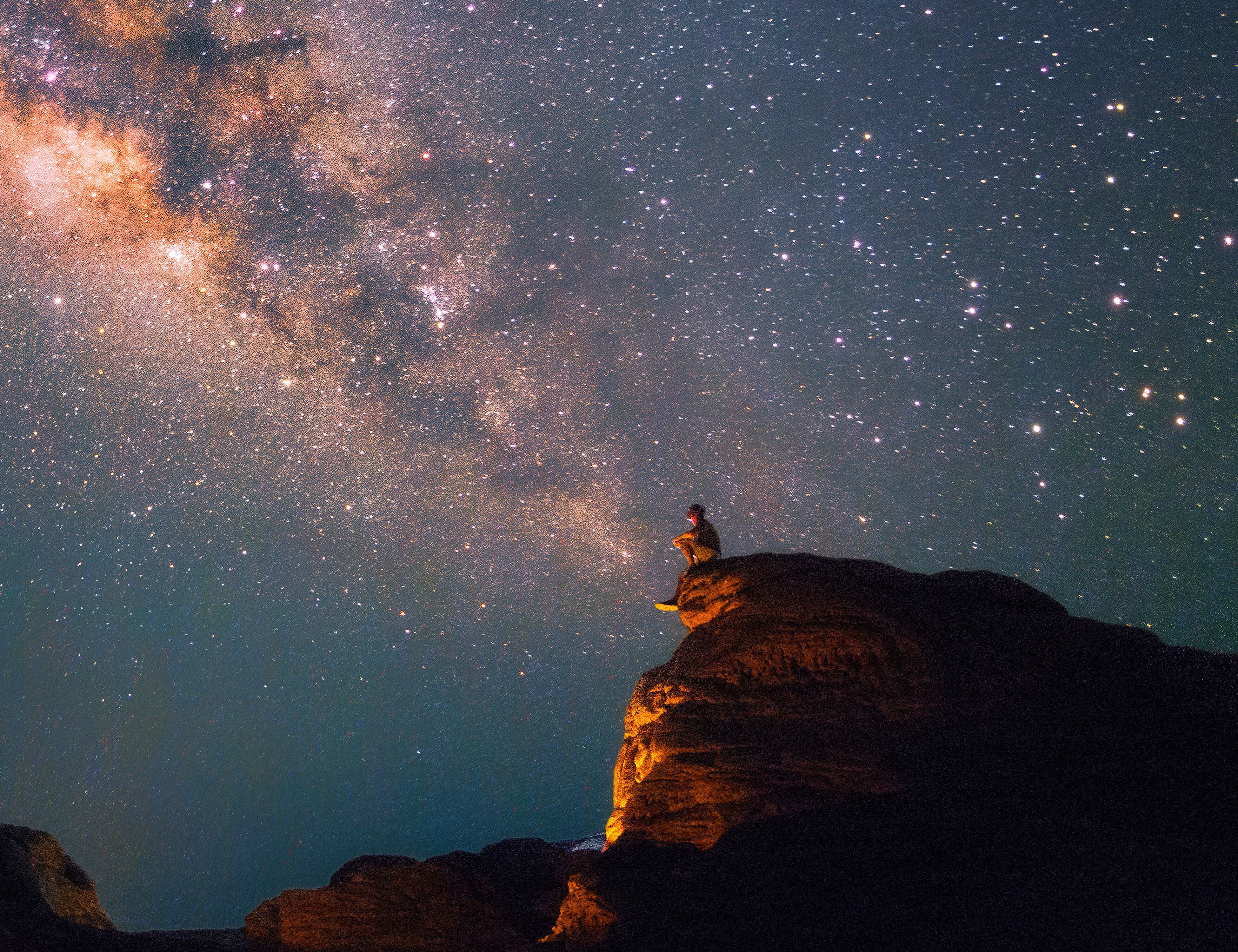 Sternklarer Nachthimmel mit leuchtender Milchstraße, darüber ein einzelner Mensch auf einem Felsen, der in die Weite des Universums blickt. Atmosphäre von Ruhe, Weite und Staunen.