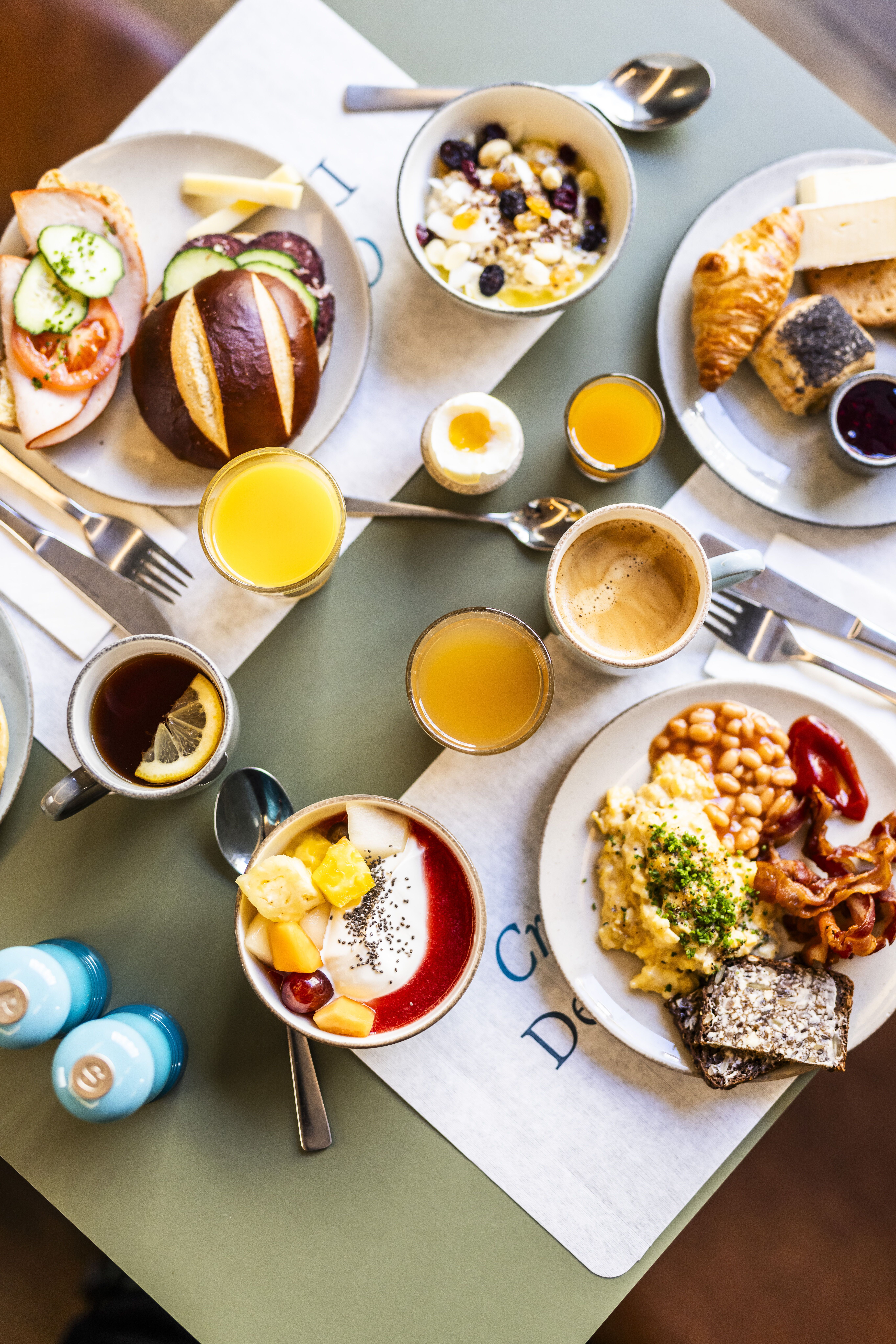 Frühstückstisch mit vielfältigen Speisen: Eier, Brot, Croissants, Müsli, Obst, Kaffee, Säfte und herzhafte sowie süße Frühstücksangebote, ansprechend angerichtet für einen genussvollen Start in den Tag.