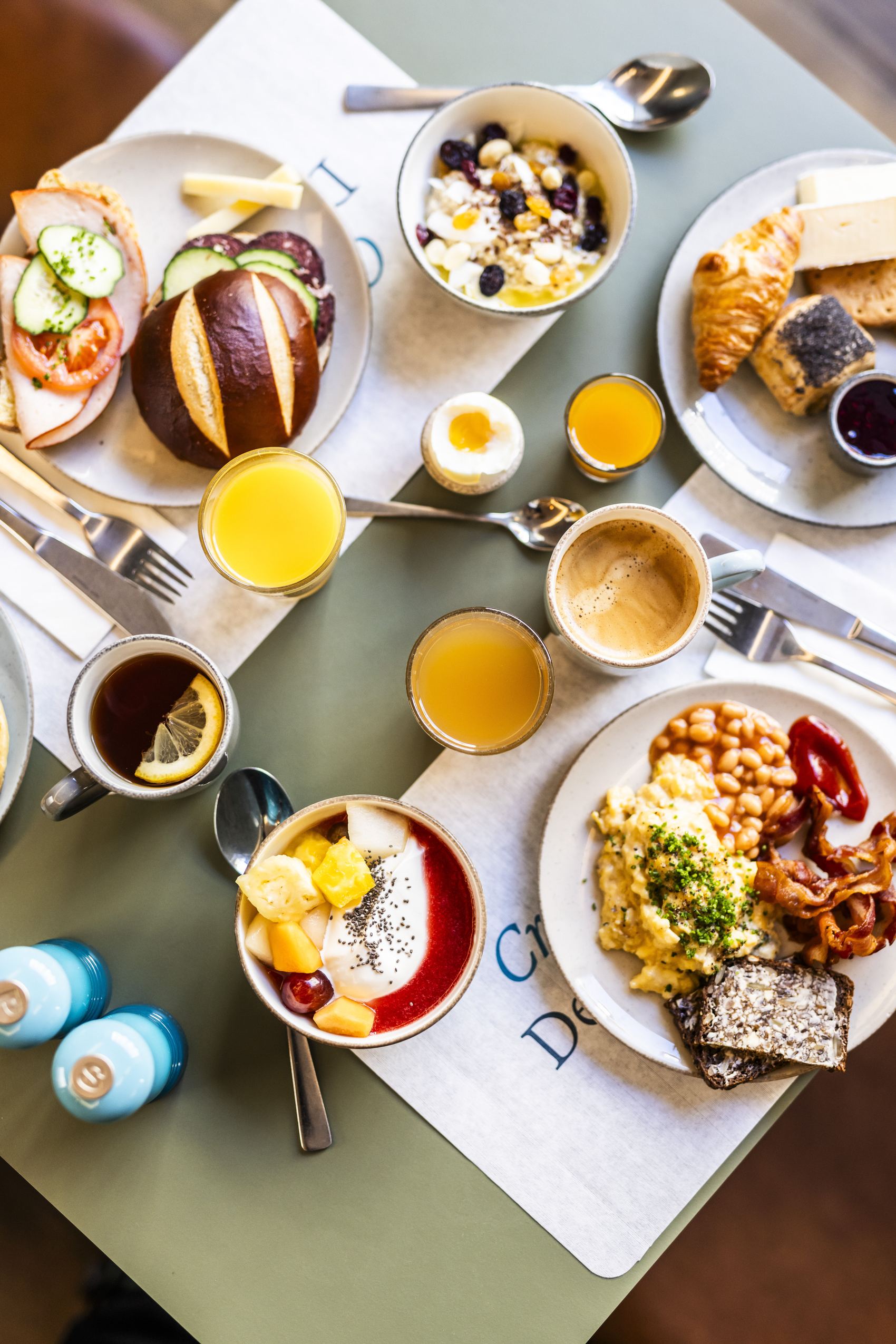Frühstückstisch mit vielfältigen Speisen: Eier, Brot, Croissants, Müsli, Obst, Kaffee, Säfte und herzhafte sowie süße Frühstücksangebote, ansprechend angerichtet für einen genussvollen Start in den Tag.