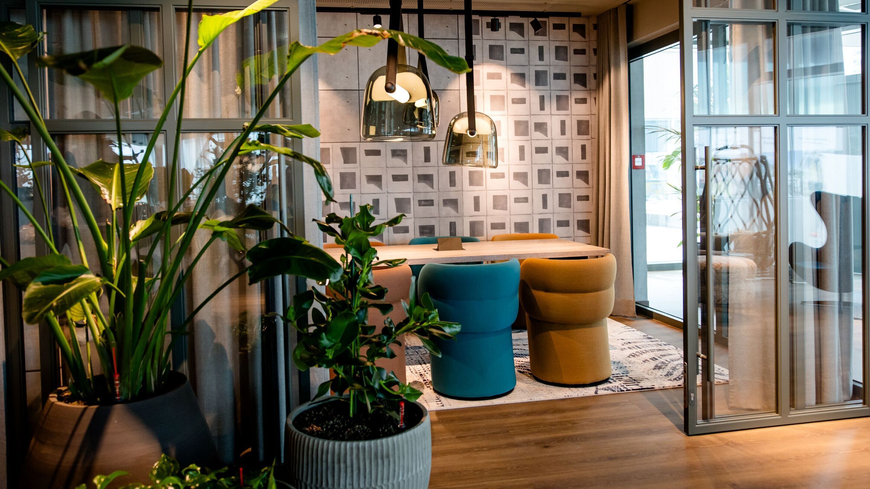 Hotel Vienna Donau City Motel One view through an open glass door into a meeting room with plants in the foreground