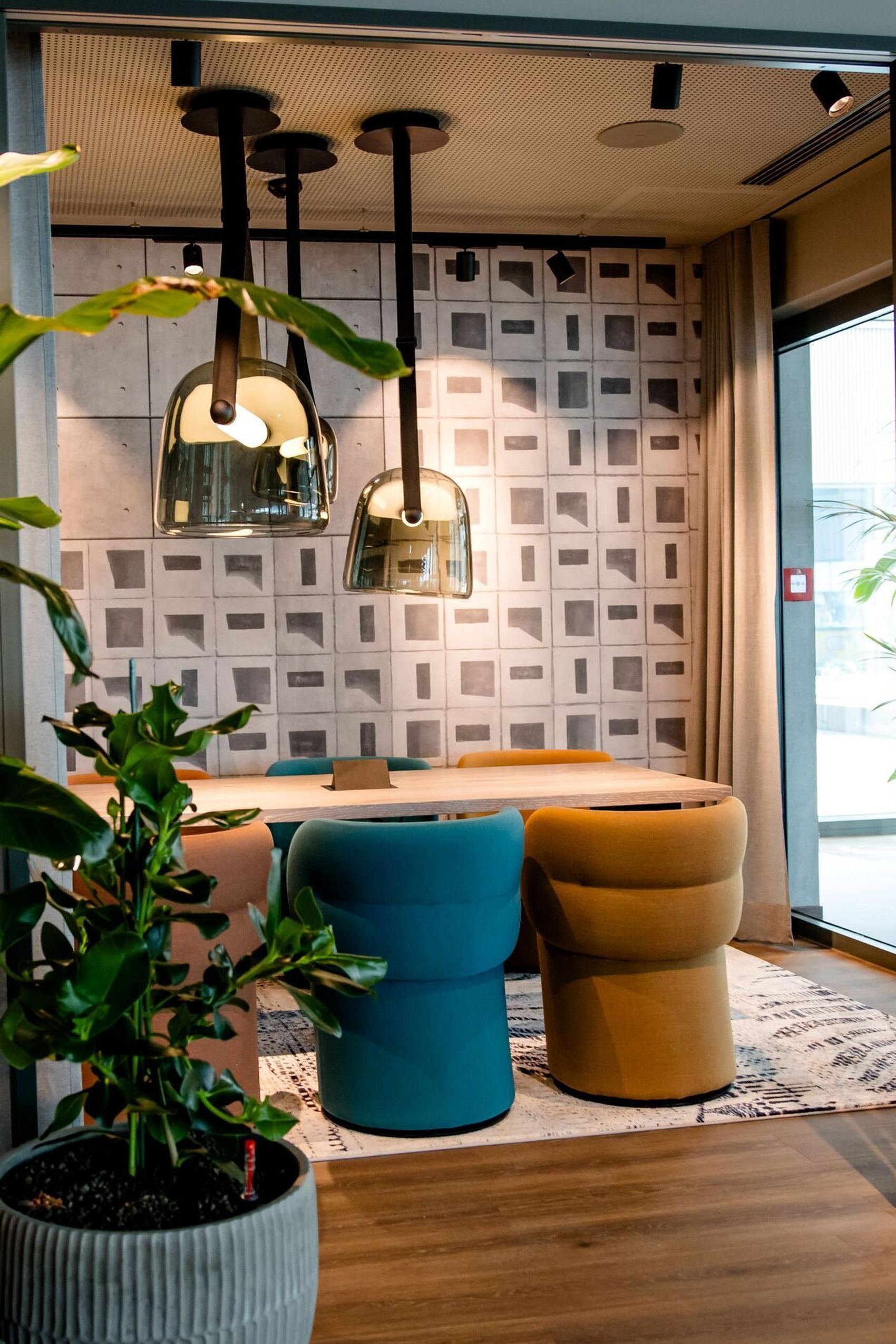 Hotel Vienna Donau City Motel One view through an open glass door into a meeting room with plants in the foreground