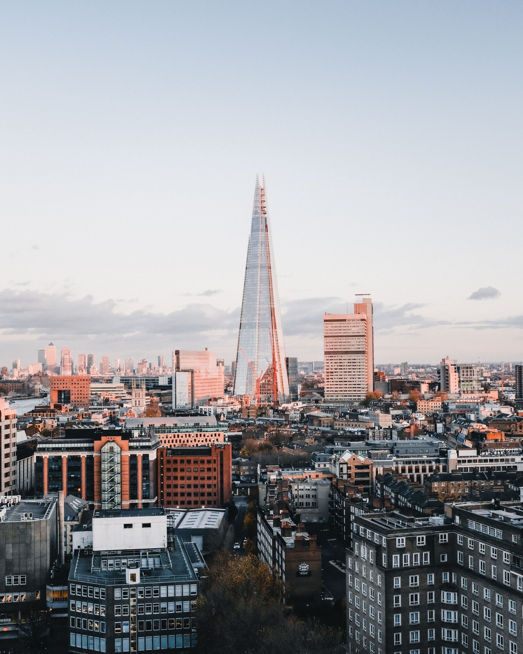Blick auf die Londoner Skyline bei Tageslicht, mit dem markanten, pyramidenförmigen The Shard im Zentrum, umgeben von modernen und historischen Gebäuden.