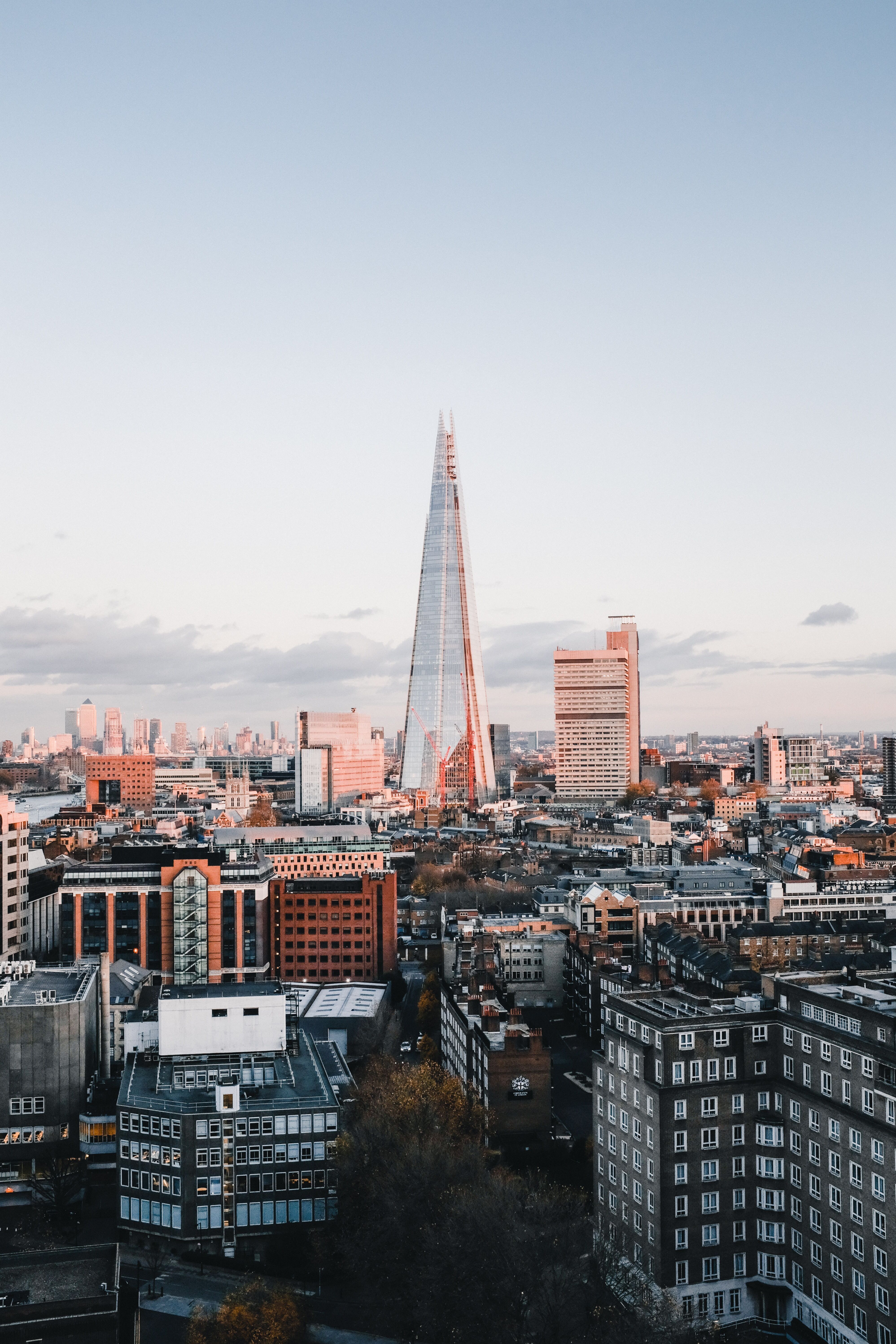 Blick auf die Londoner Skyline bei Tageslicht, mit dem markanten, pyramidenförmigen The Shard im Zentrum, umgeben von modernen und historischen Gebäuden.