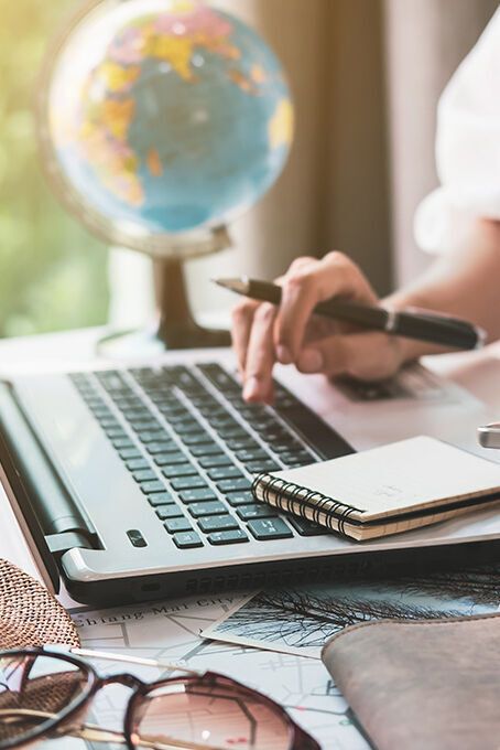 Eine Frau im Office am PC plant Brückentage mit ihrem Kalender