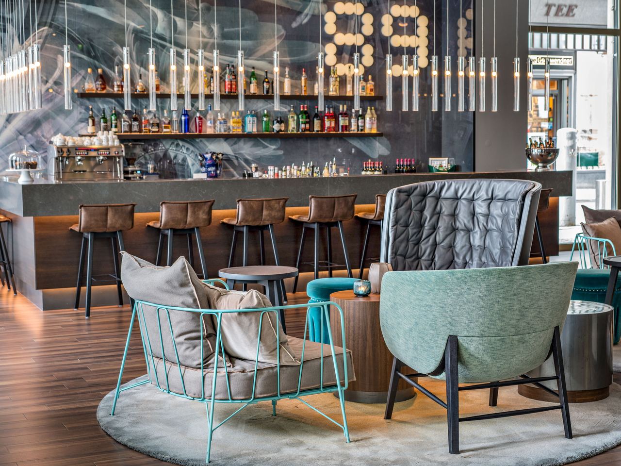 Motel One Hotelbar mit stilvollen Sitzgelegenheiten, gemütlichen Sesseln und Barhockern. Dezente Beleuchtung und ein gut bestücktes Getränkeangebot.