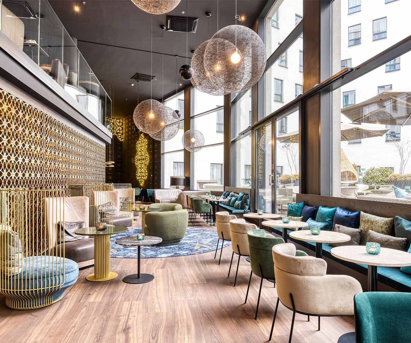 Hotel Brüssel Motel One lichtdurchflutete Lounge mit Sitzgelegenheiten und großer Fensterfront sowie Zugang zur Terrasse 