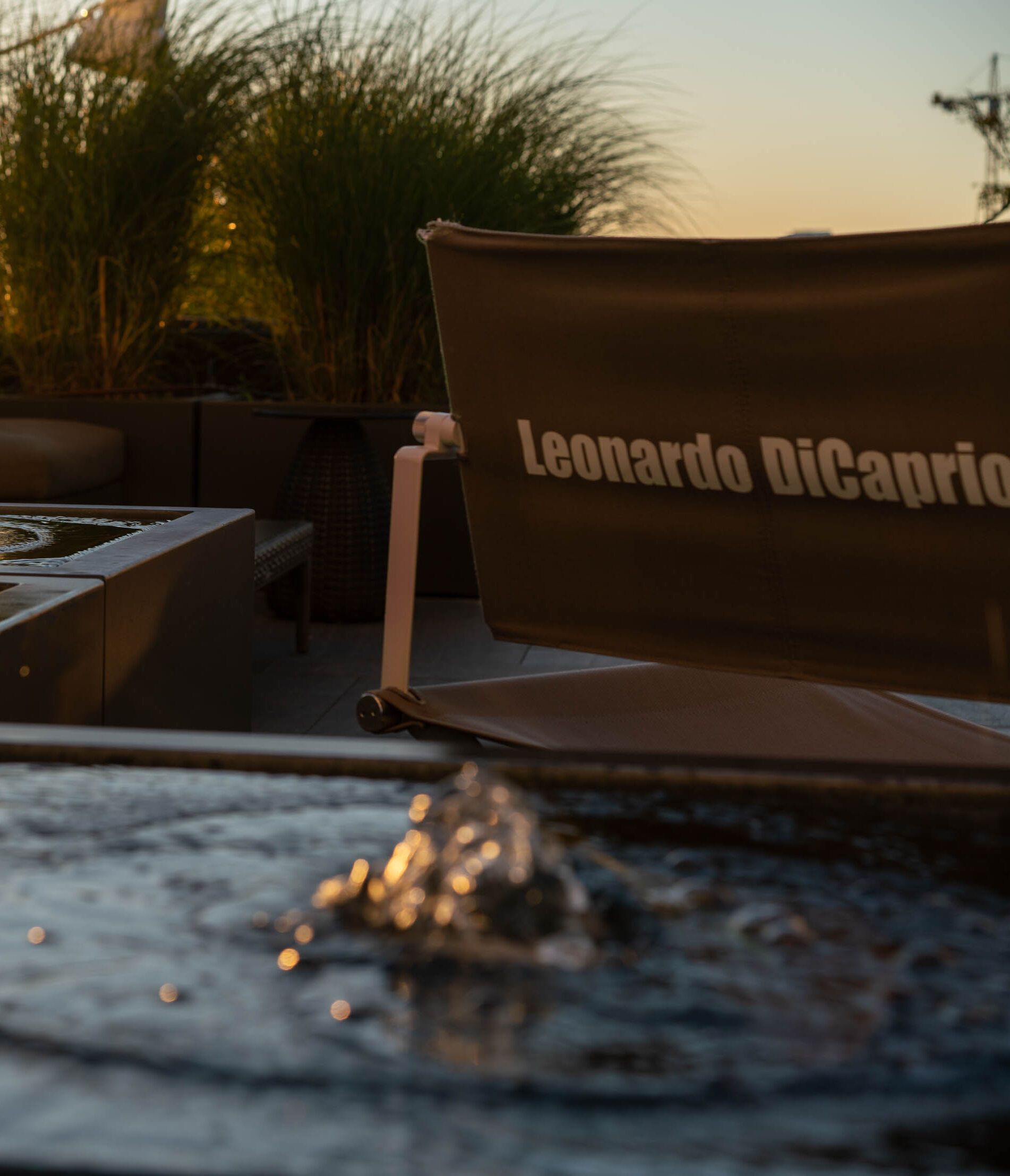 Loungebereich mit gemütlichen Sitzmöbeln und Wasserfontänen bei Sonnenuntergang