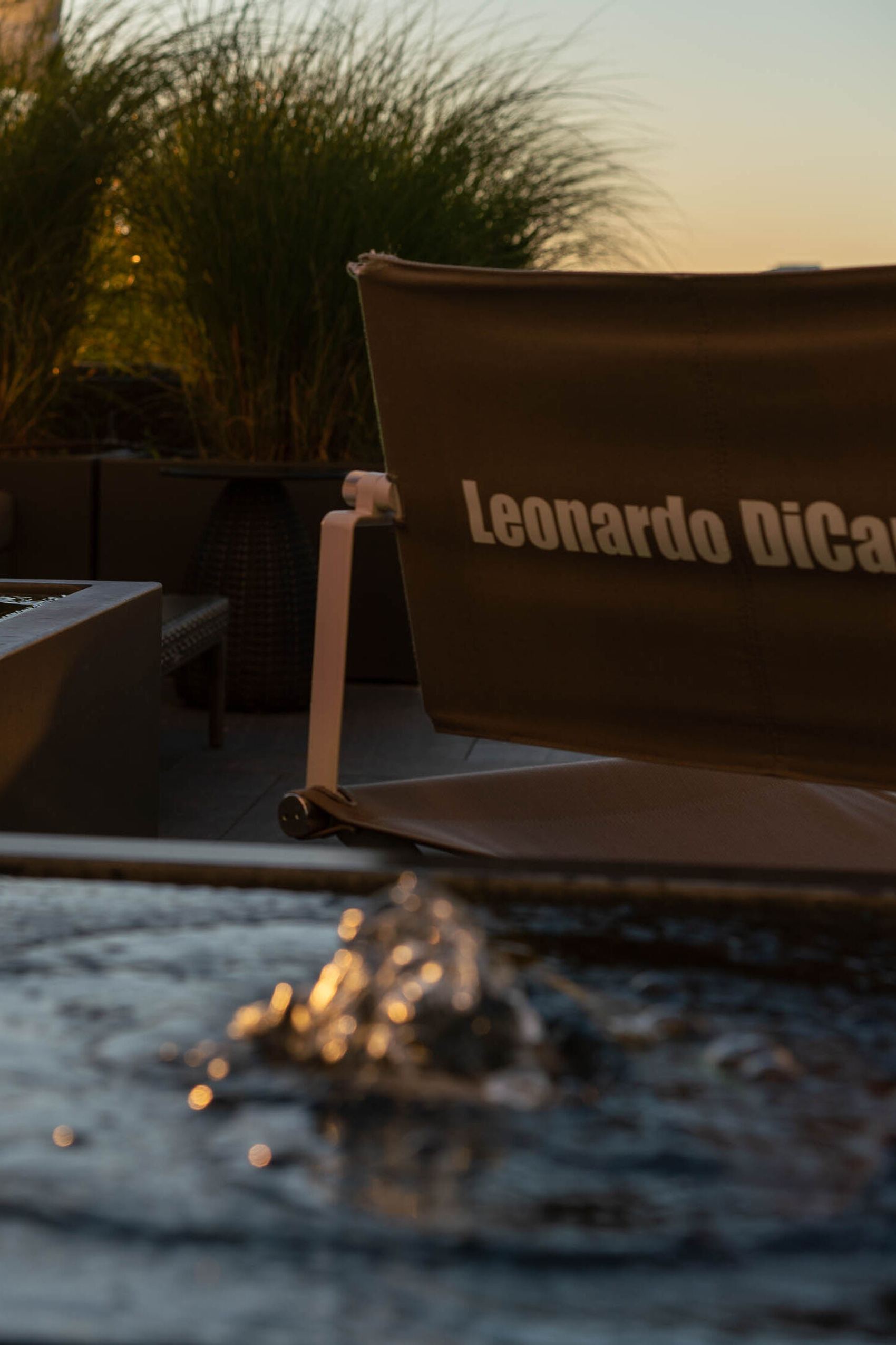 Loungebereich mit gemütlichen Sitzmöbeln und Wasserfontänen bei Sonnenuntergang