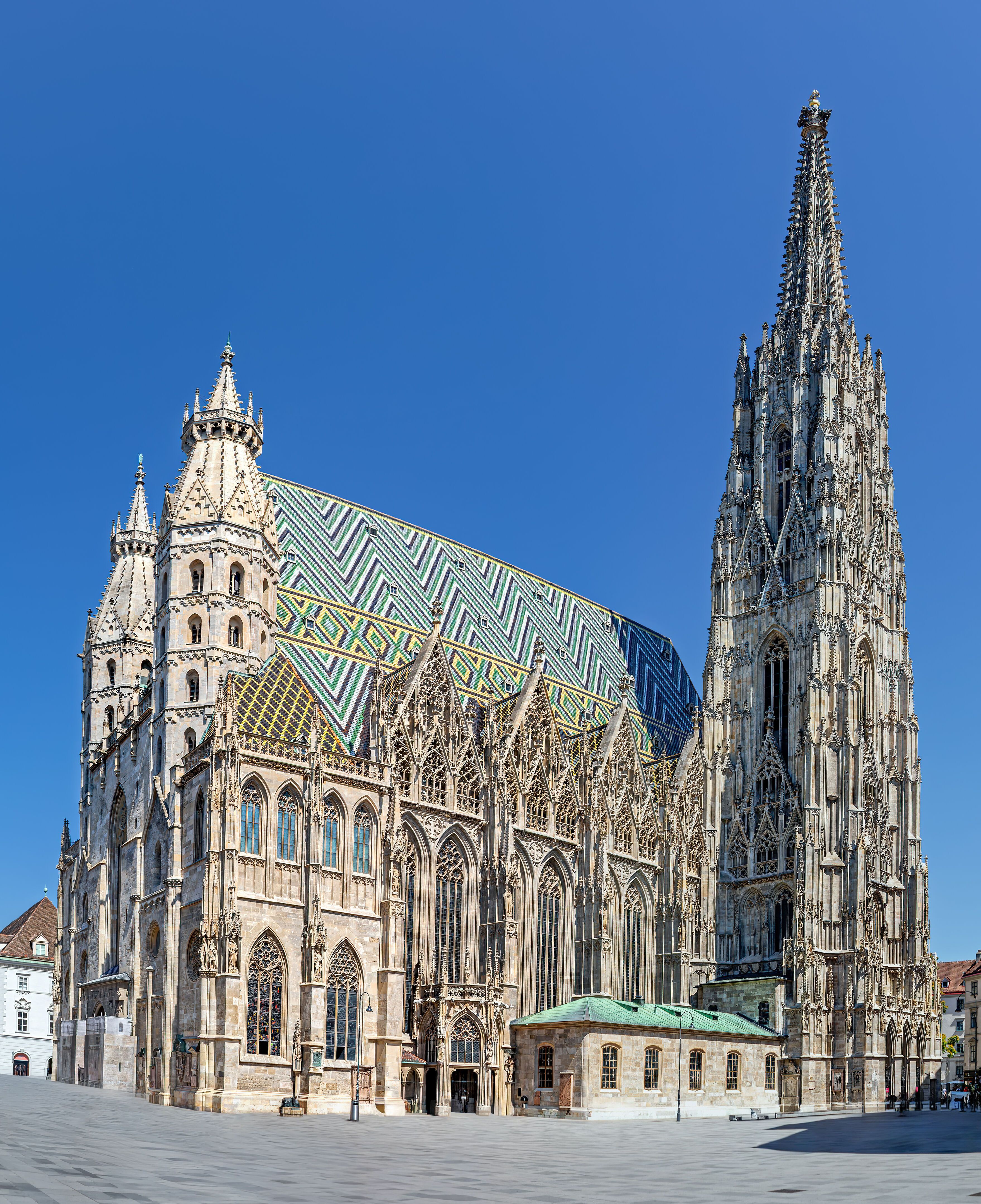 Gotischer Stephansdom in Wien mit farbigem Ziendach und hohem Turm unter klarem blauem Himmel.