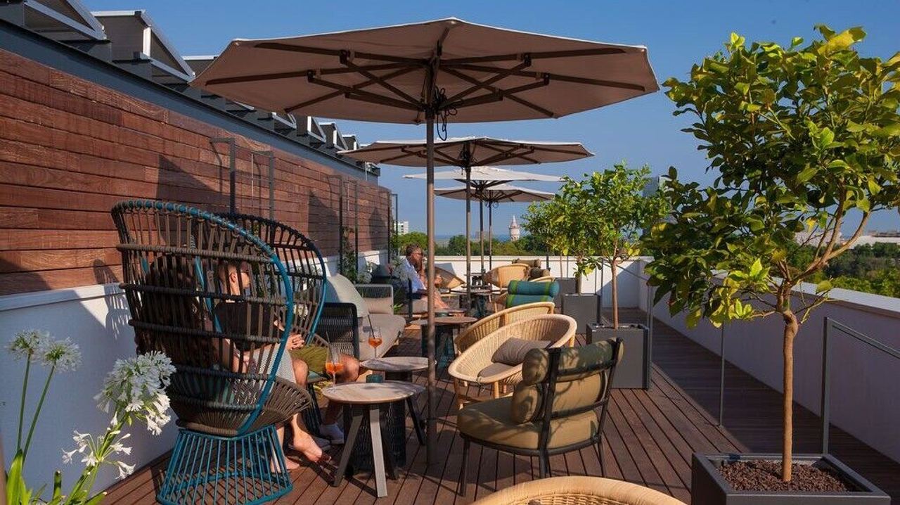 Dachterrasse mit gemütlichen Sitzgruppen, Sonnenschirmen und Pflanzen.