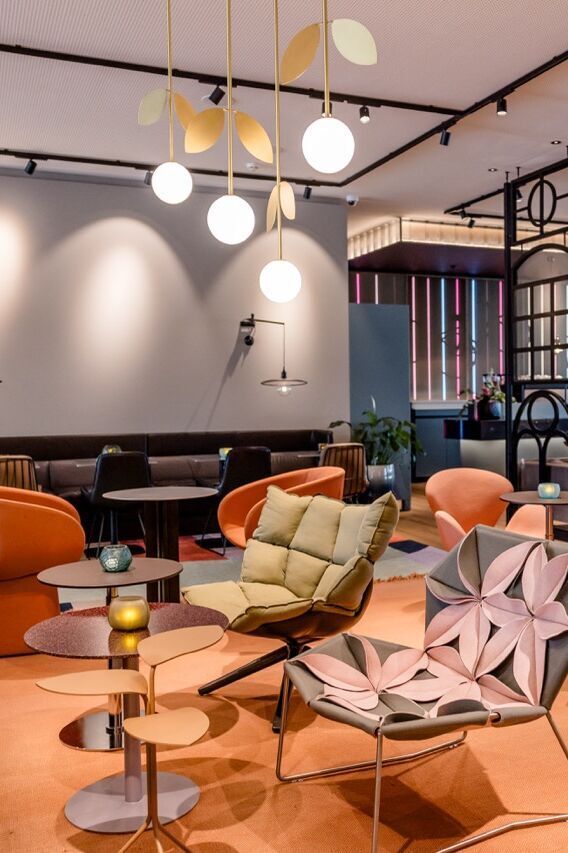 Moderne Lounge mit stilvollen Sesseln und Sofas, warmem Licht und offenen Raumstrukturen, die zum Entspannen und geselligen Beisammensein einladen.