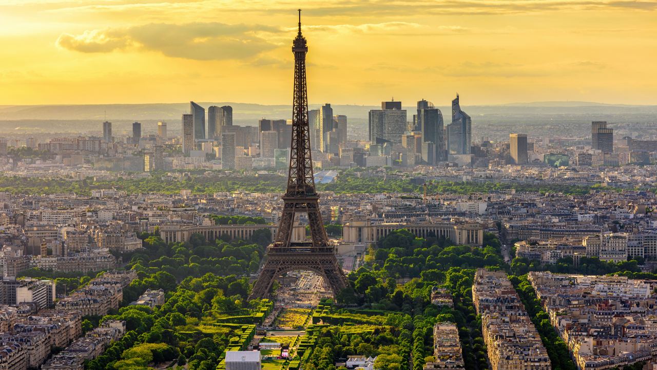 Panoramablick auf den Eiffelturm in Paris bei Sonnenuntergang, umgeben von grünen Parks und der modernen Skyline von La Défense im Hintergrund. Panoramablick auf den Eiffelturm in Paris bei Sonnenuntergang, umgeben von grünen Parks und der modernen Skyline von La Défense im Hintergrund.