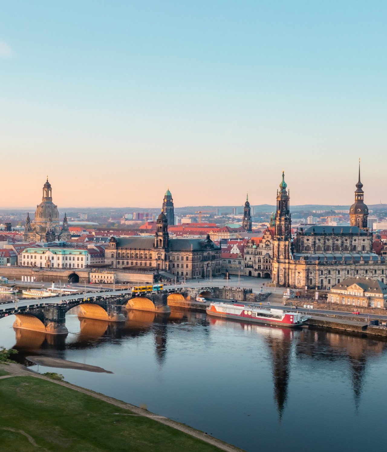 Panoramablick auf die historische Altstadt von Dresden mit der Elbe, einer Brücke und markanten barocken Türmen im sanften Licht des Sonnenuntergangs. Panoramablick auf die historische Altstadt von Dresden mit der Elbe, einer Brücke und markanten barocken Türmen im sanften Licht des Sonnenuntergangs.