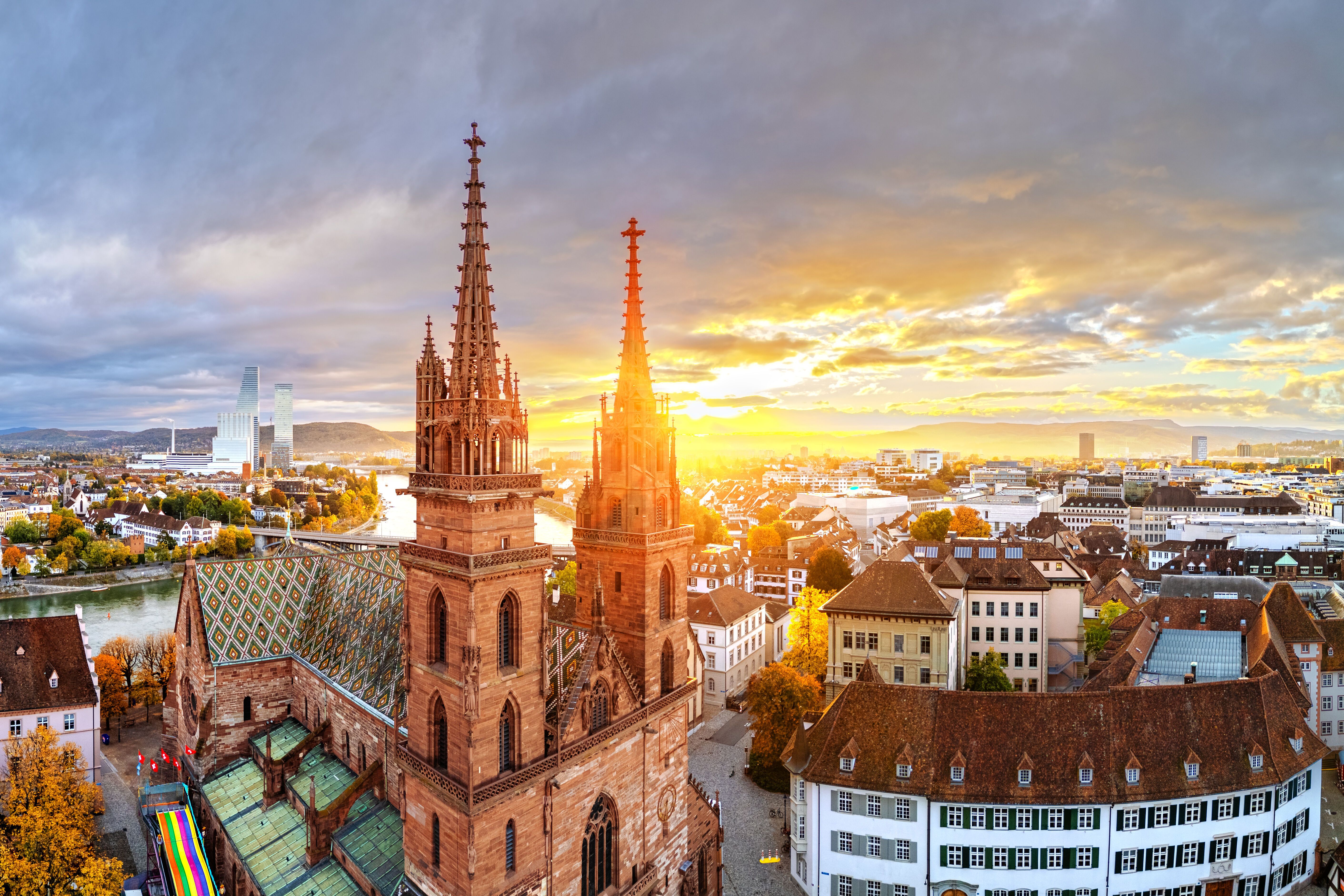Sonnenuntergang über der historischen Altstadt mit markanter gotischer Kirche und bunten Herbstbäumen, die eine warme und einladende Atmosphäre schaffen.