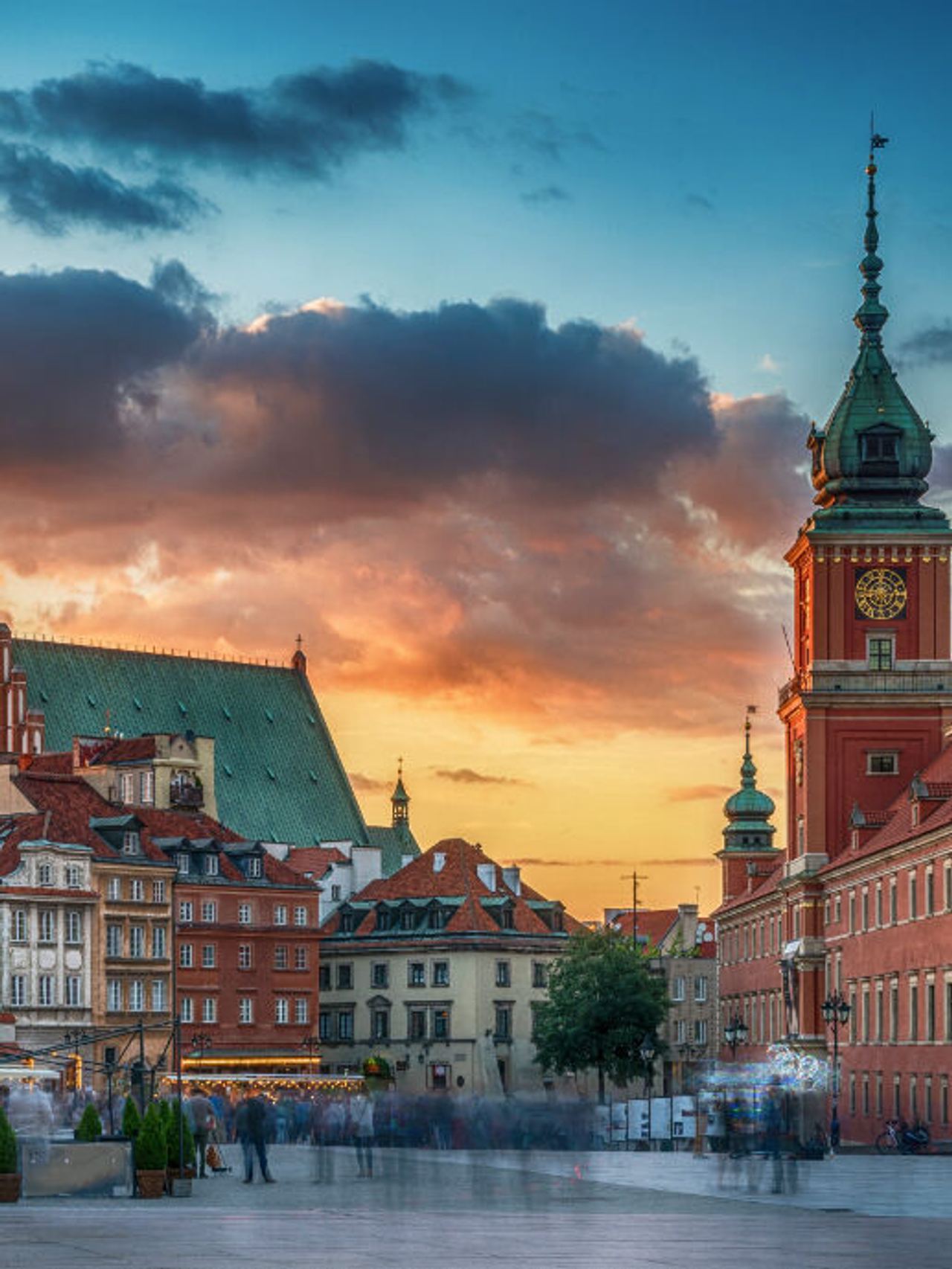 Historische Altstadt mit farbenfrohen Häusern und turmhohen Bauwerken im warmen Abendlicht, malerischer Sonnenuntergang am Himmel, lebendiger Marktplatz mit Menschen in Bewegung. Historische Altstadt mit farbenfrohen Häusern und turmhohen Bauwerken im warmen Abendlicht, malerischer Sonnenuntergang am Himmel, lebendiger Marktplatz mit Menschen in Bewegung.