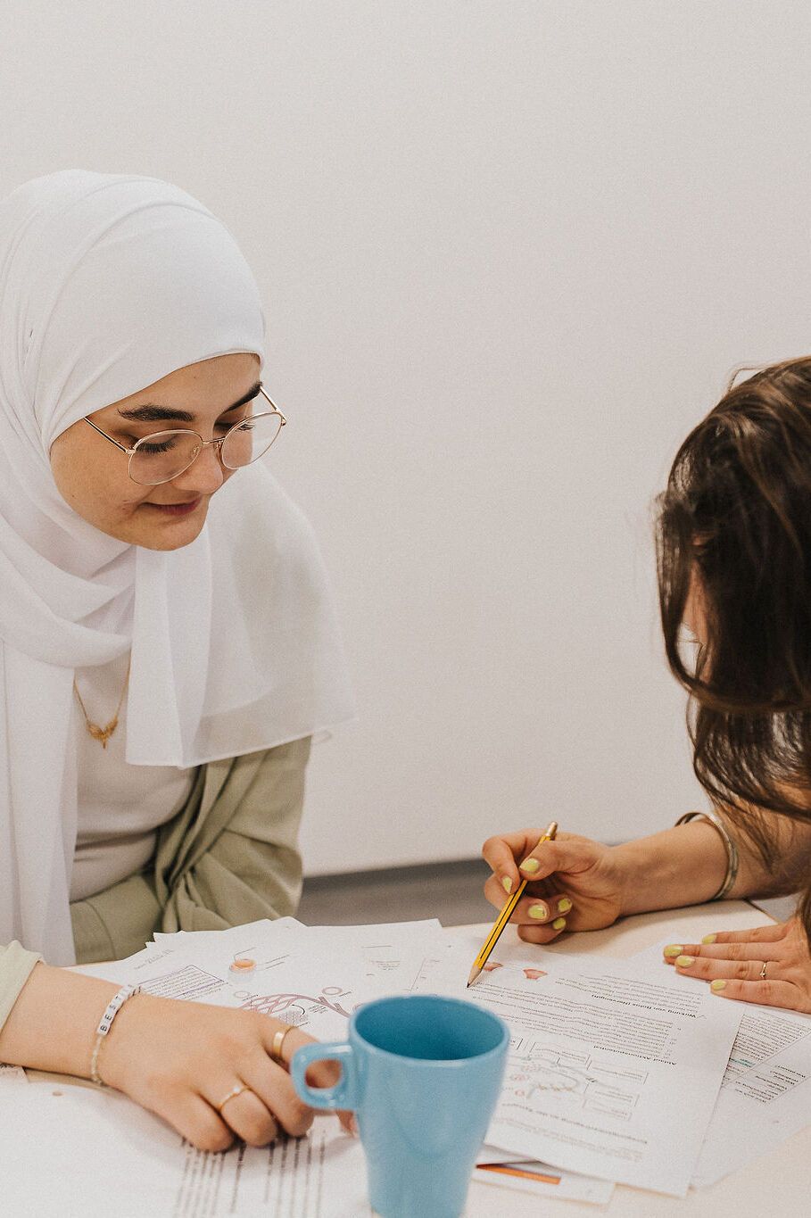Zwei Frauen arbeiten gemeinsam an Dokumenten, konzentriert und kooperativ, in einer entspannten Lern- oder Arbeitssituation.