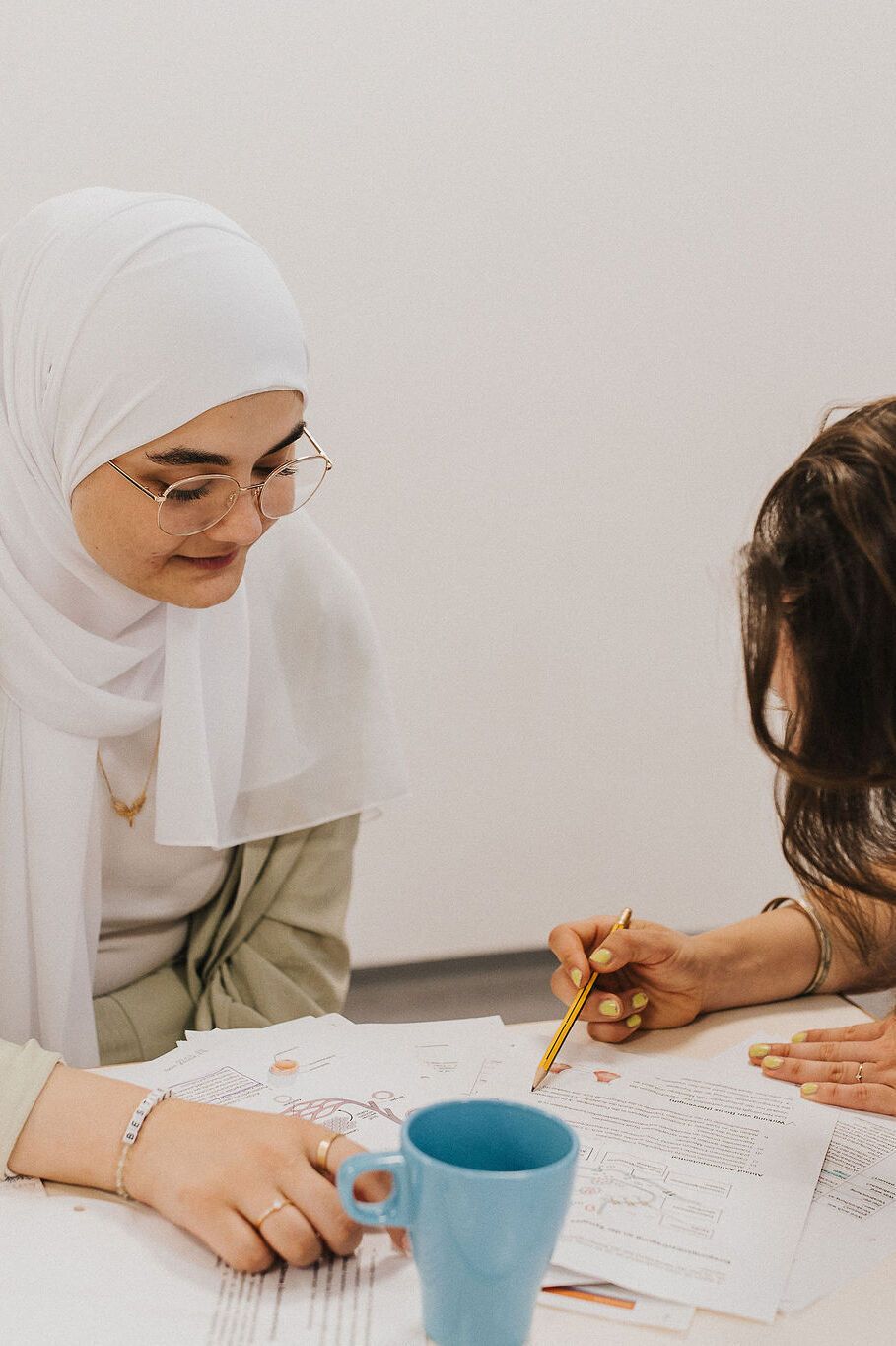 Zwei Frauen arbeiten gemeinsam an Dokumenten, konzentriert und kooperativ, in einer entspannten Lern- oder Arbeitssituation.