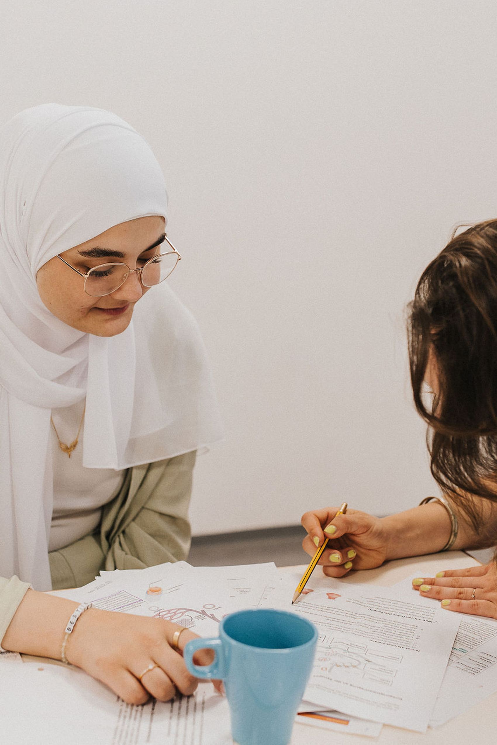 Zwei Frauen arbeiten gemeinsam an Dokumenten, konzentriert und kooperativ, in einer entspannten Lern- oder Arbeitssituation.