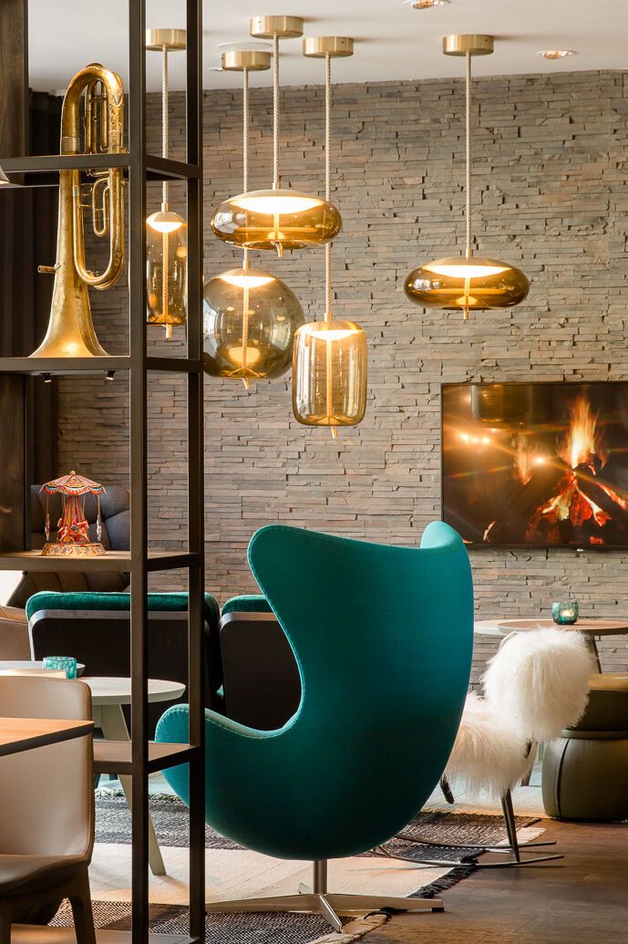 hotel Munich Westend Motel One light-flooded lounge with egg chair and open shelf with decoration