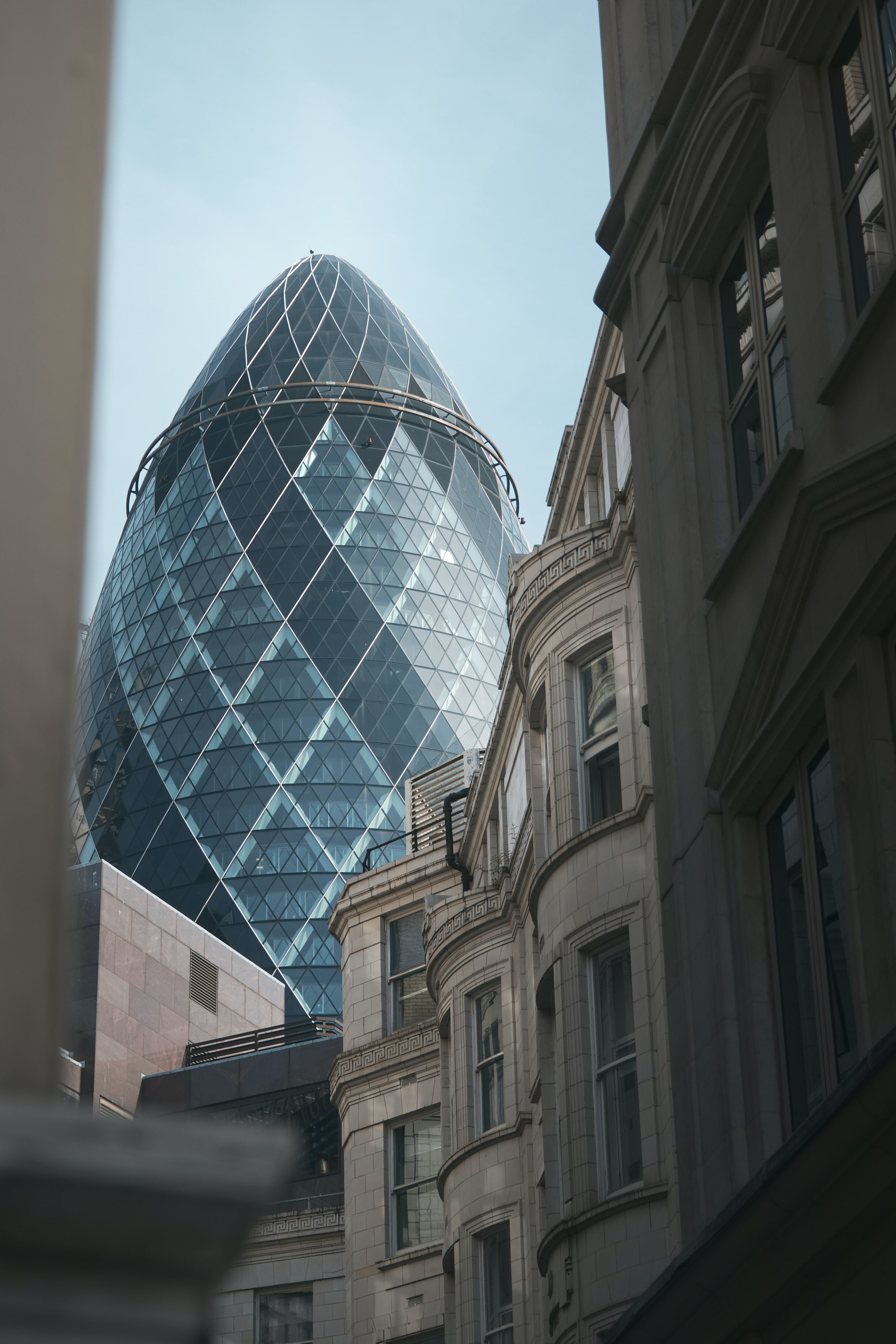 Blick auf das moderne, gläserne Hochhaus „The Gherkin“ in London, umgeben von historischen, klassischen Gebäuden.