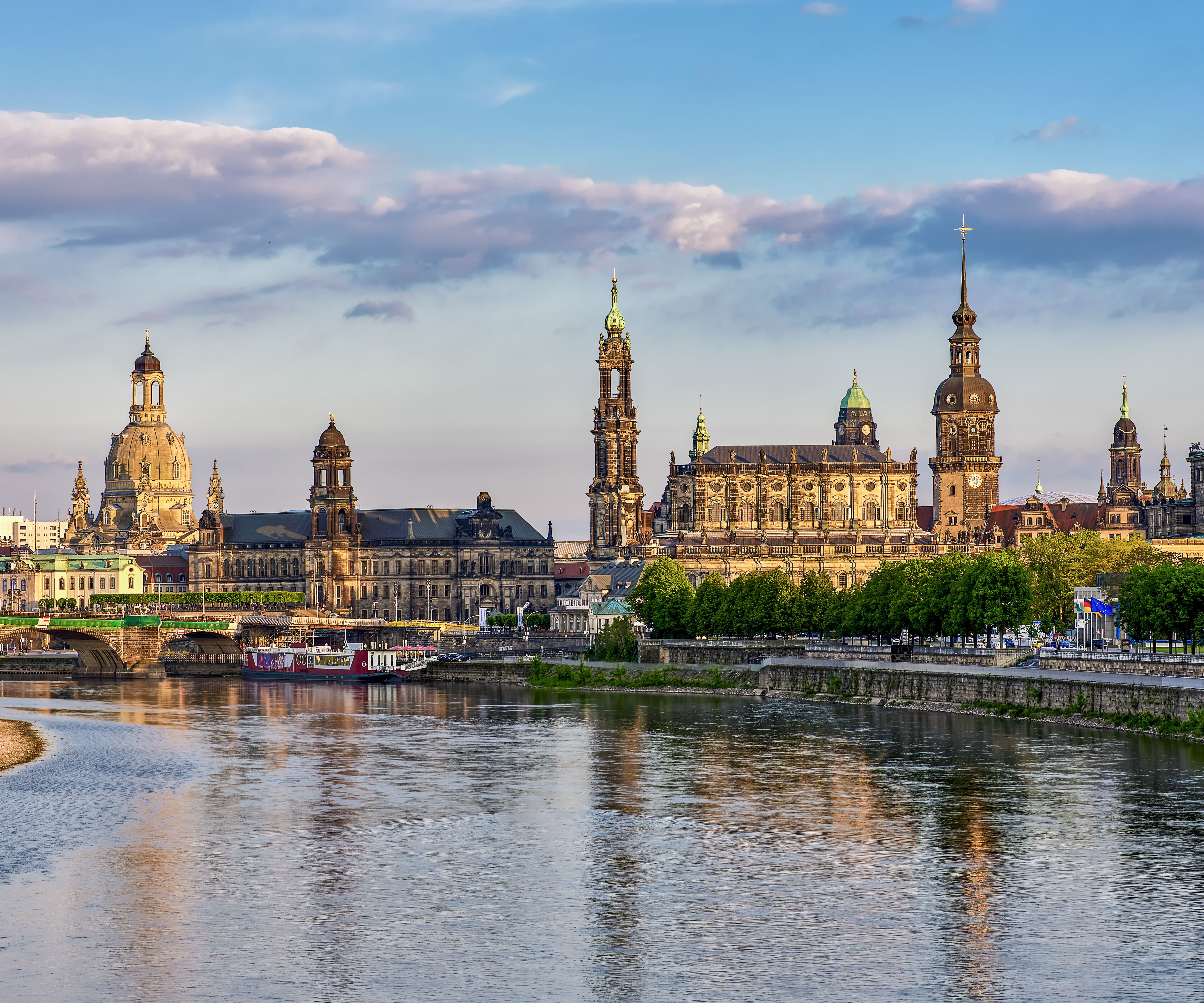 Panoramablick auf die historische Altstadt von Dresden mit Elbufer, markanten Kirchtürmen und klassischer Architektur unter blauem Himmel.