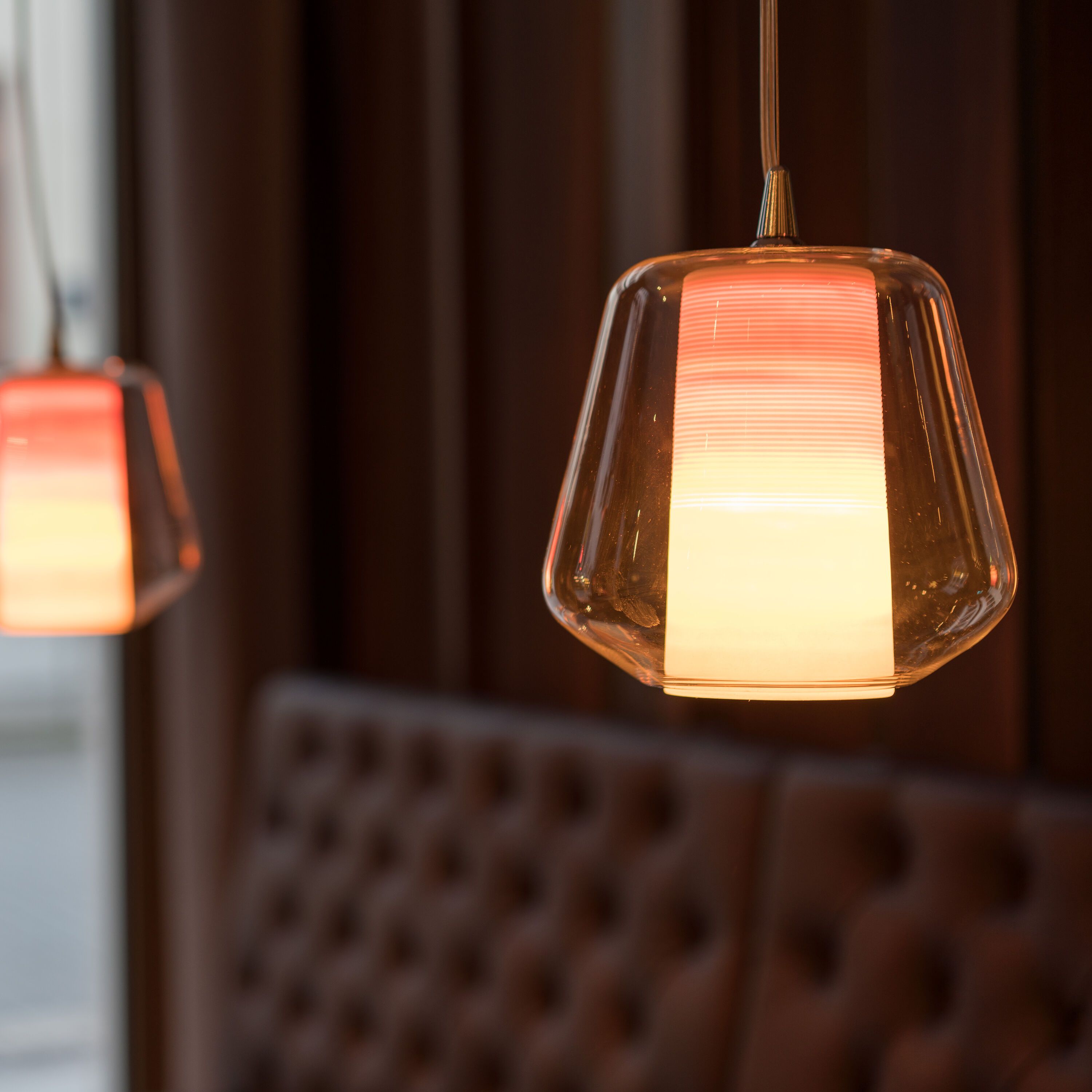 Warm leuchtende, moderne Hängeleuchten über einem gepolsterten Sitzbereich