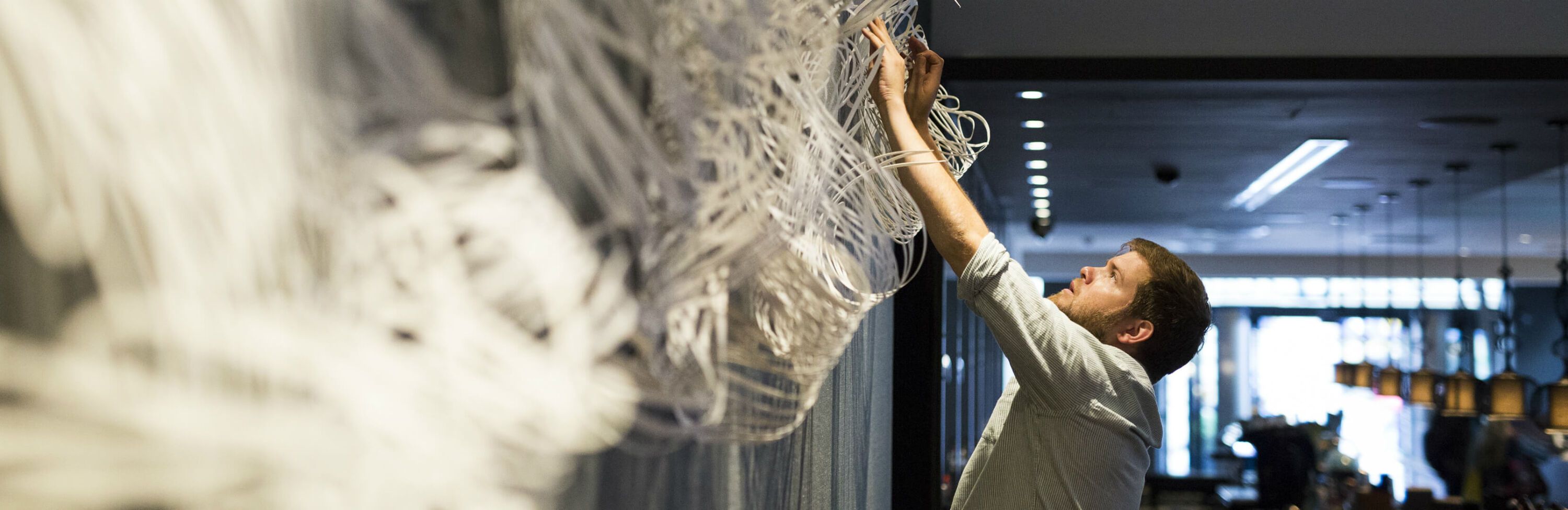 Mann hängt Kunst aus Baumwolle im Motel One Hotel auf